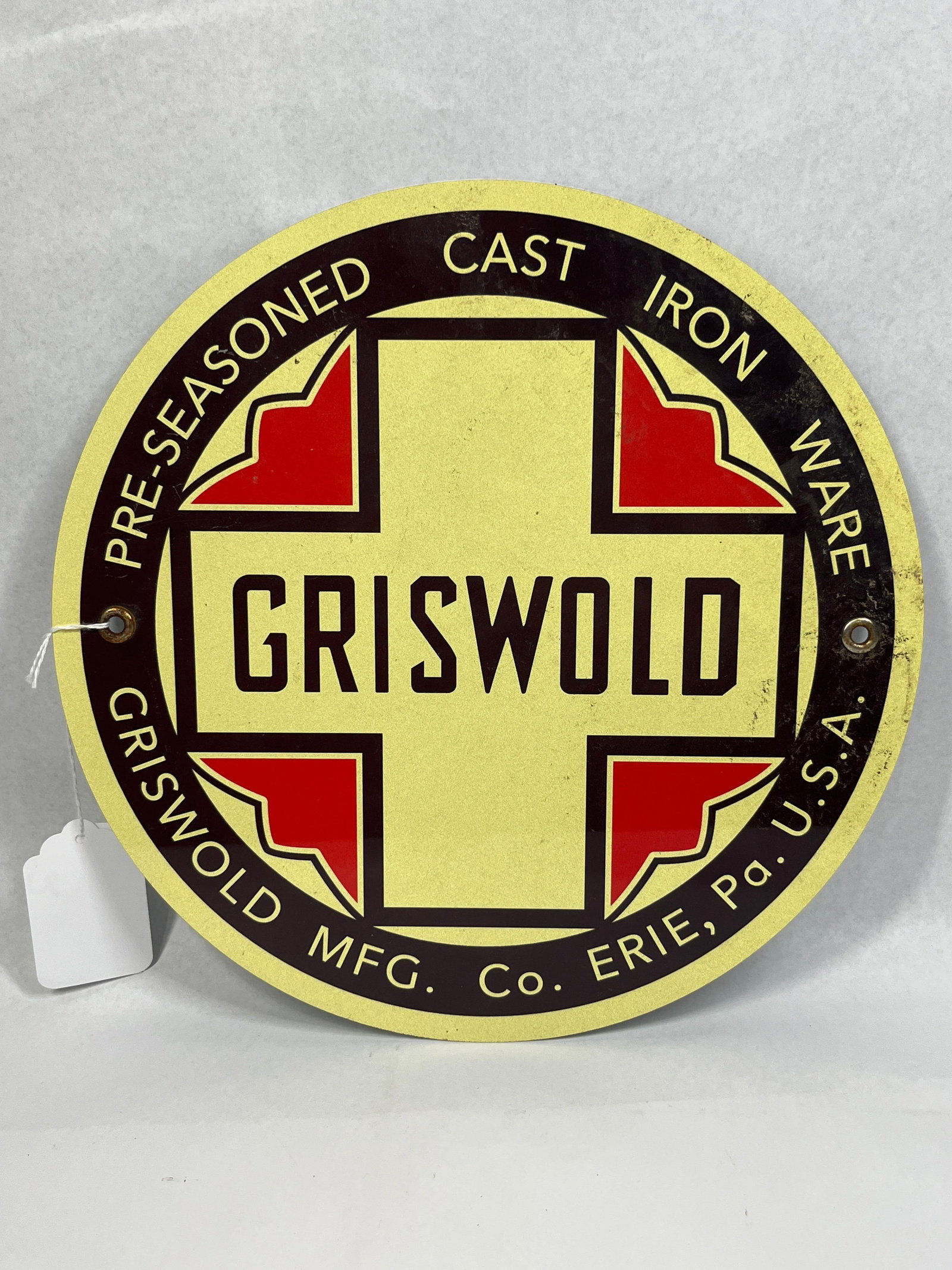 Griswold Cast Iron Advertising Sign: 12in dia. This circular advertising sign features the branding for the Griswold Manufacturing Co., a company historically based in Erie, Pennsylvania, known for its cast iron cookware. The sign is
