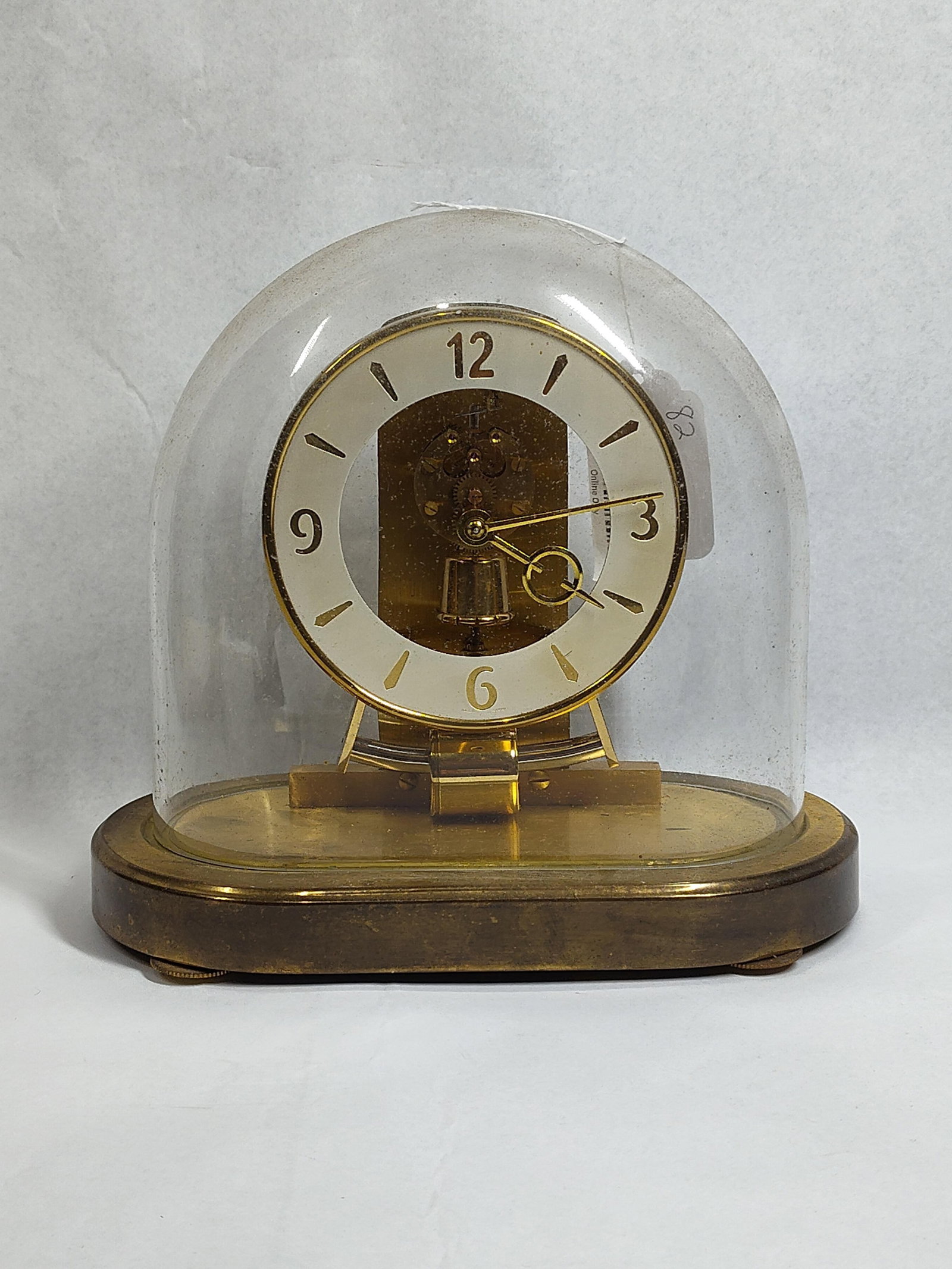 Kieninger & Obergfell Kundo Clock: 9.5x8.5 A Kieninger & Obergfell (Kundo) electromagnetic mantel clock. The clock features a torsion-style movement housed beneath a clear glass dome. The design includes a brass-finished metal base