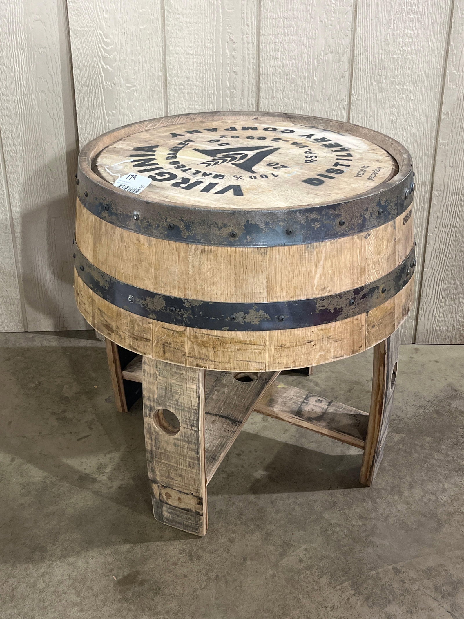 Va. Distillery Oak Barrel Side Table: 22x22x26 A rustic side table crafted from a reclaimed wooden spirits barrel. The circular tabletop is fashioned from a barrel head and features black stenciled graphics including a central stylized V
