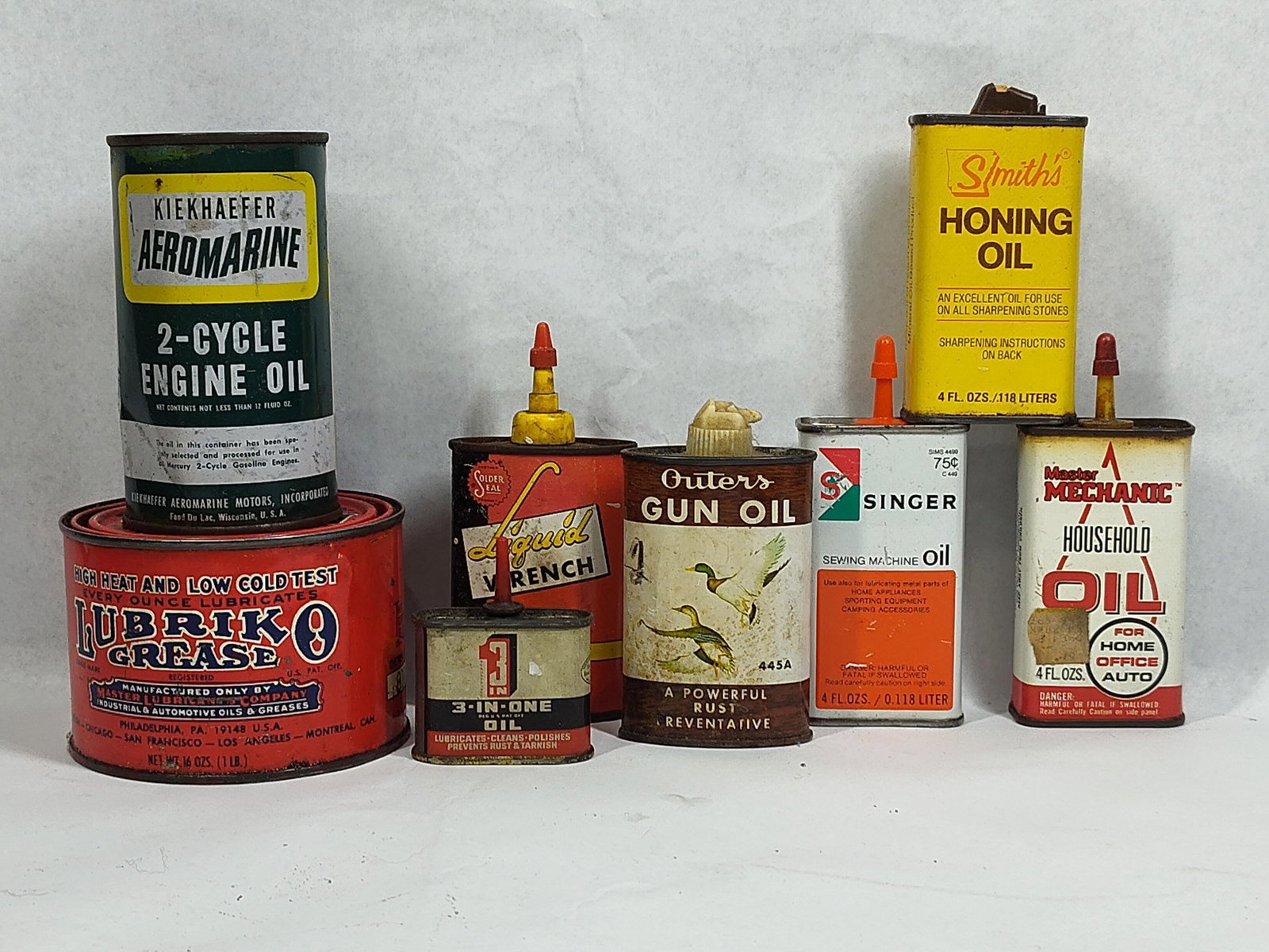 Set 8 Advertising Oil & Grease Tins: This lot features a collection of eight vintage metal containers for oil and grease from various American manufacturers, primarily dating from the mid-20th century. The set includes a cylindrical