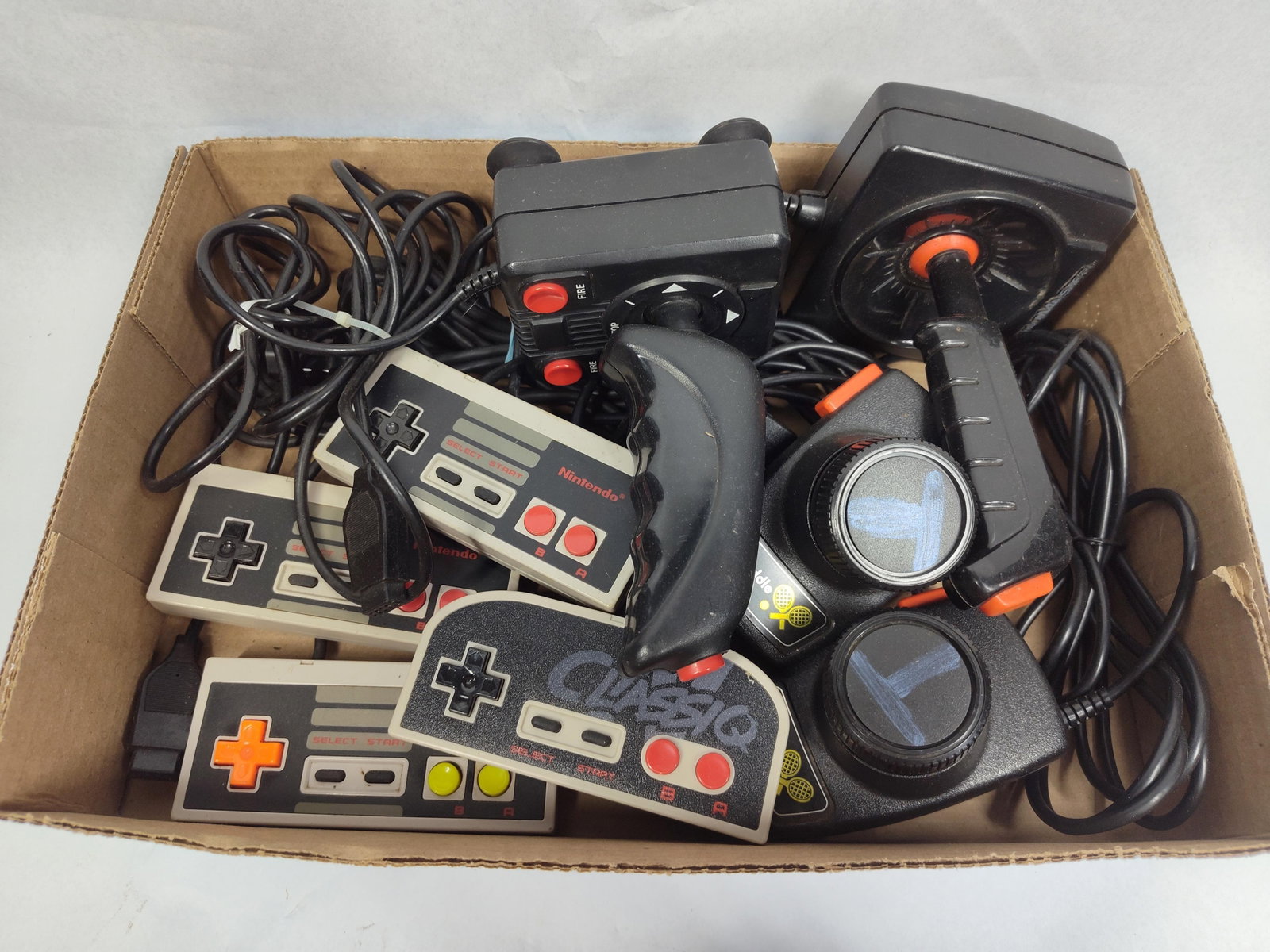 Video Game Controllers & Joysticks: This collection includes a variety of vintage video game peripherals designed for use with 8-bit era home consoles. The group features several controllers compatible with the Nintendo Entertainment