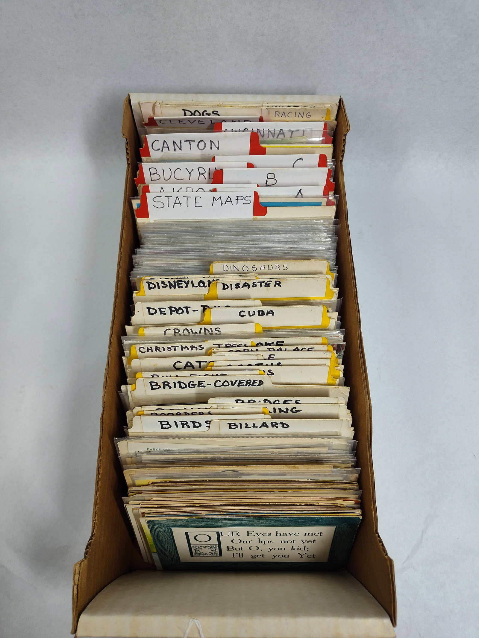 & Mid-C. Postcard Storage Archive: A large, categorized collection of vintage and mid-century postcards housed in a cardboard storage tray with top-tab dividers. The archive is organized by both geographic location and thematic