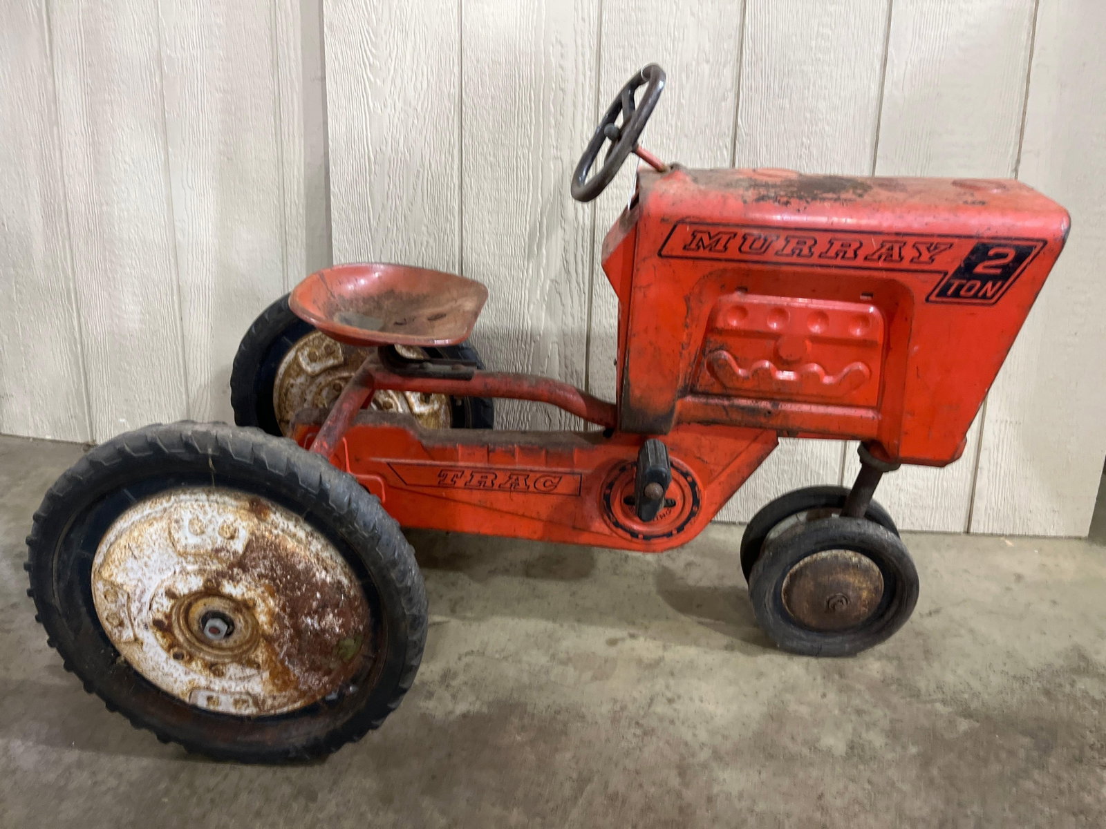 Murray 2 Ton Trac Vintage Pedal Tractor: This vintage pedal tractor was manufactured by the Murray Ohio Manufacturing Company. It features a pressed steel body and frame with a tricycle-style wheel configuration. The tractor is finished in