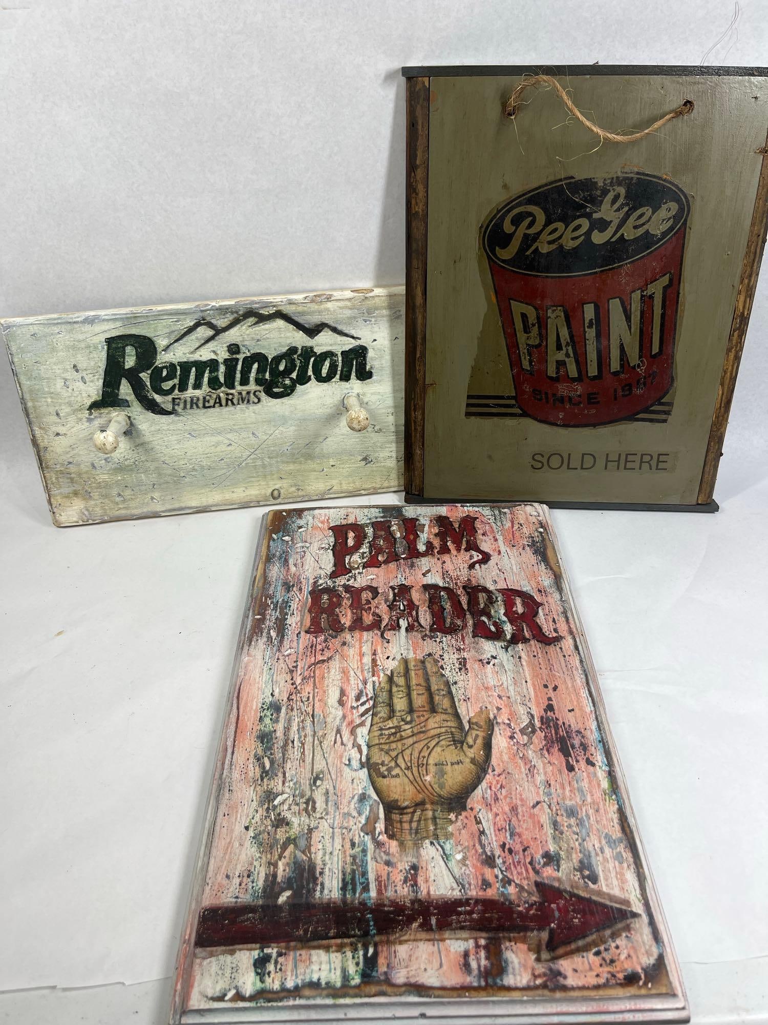 Trio Modern Distressed Wood Signs: A collection of three contemporary decorative wooden signs designed to emulate the appearance of vintage advertising. The first sign is a wall-mounted peg rack featuring a rectangular board with two