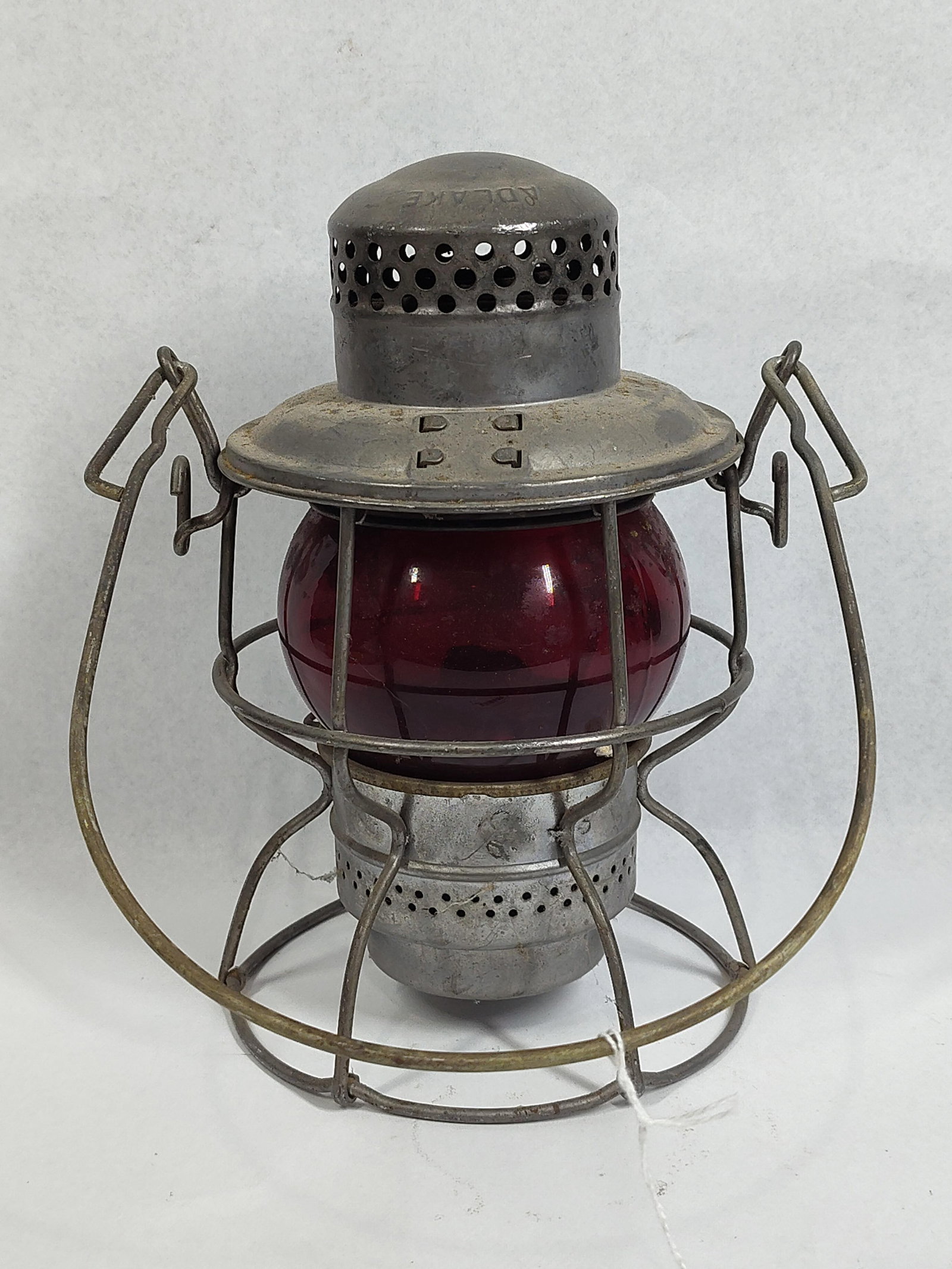 Adlake Kero Railroad Lantern, Red Globe: 9in A vintage Adlake Kero model railroad lantern featuring a steel wire-cage frame construction. The lantern is equipped with a short-style red glass globe, which was standard equipment for signaling 