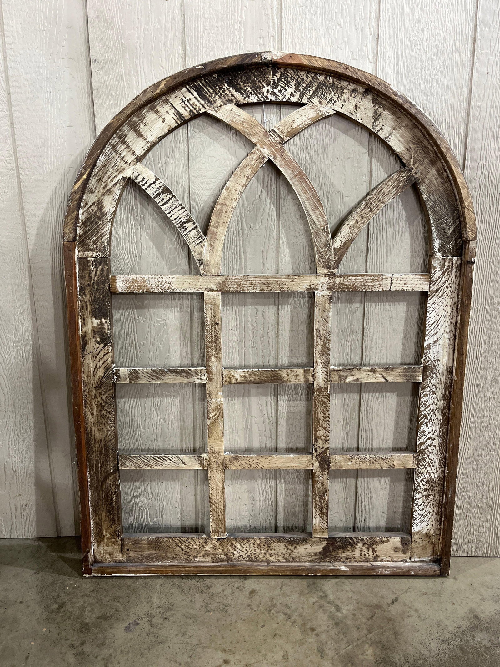 Arched Wooden Window Frame: 47.5x36 This decorative wall hanging is constructed from wood and designed in the style of an arched Gothic cathedral window frame. The structure features a rectangular grid at the base surmounted by