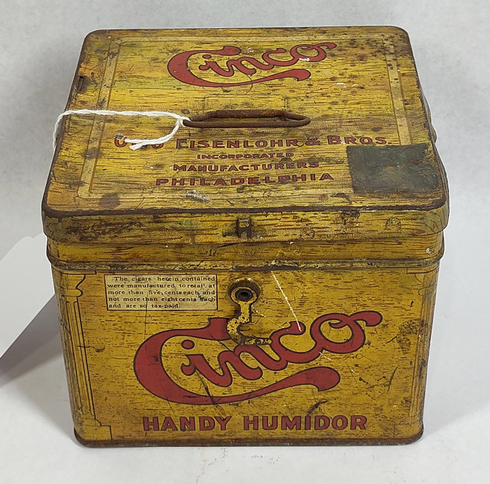 Otto Eisenlohr Cinco Cigar Tin Humidor: This is a square-format lithographed tin cigar box produced by Otto Eisenlohr and Bros., Incorporated, of Philadelphia, Pennsylvania. Designated as a Handy Humidor, the exterior features a yellow