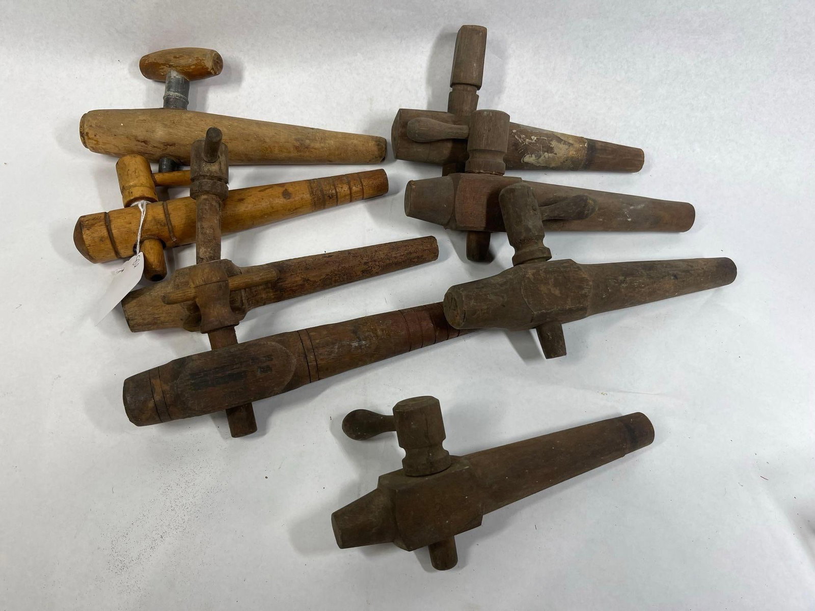 7 Wood Taps & Spigots, Sharpless Bros: A collection of seven turned hardwood barrel taps, or spigots, designed for use with wooden casks and kegs. The assortment includes various sizes and shapes, with most constructed entirely of wood.