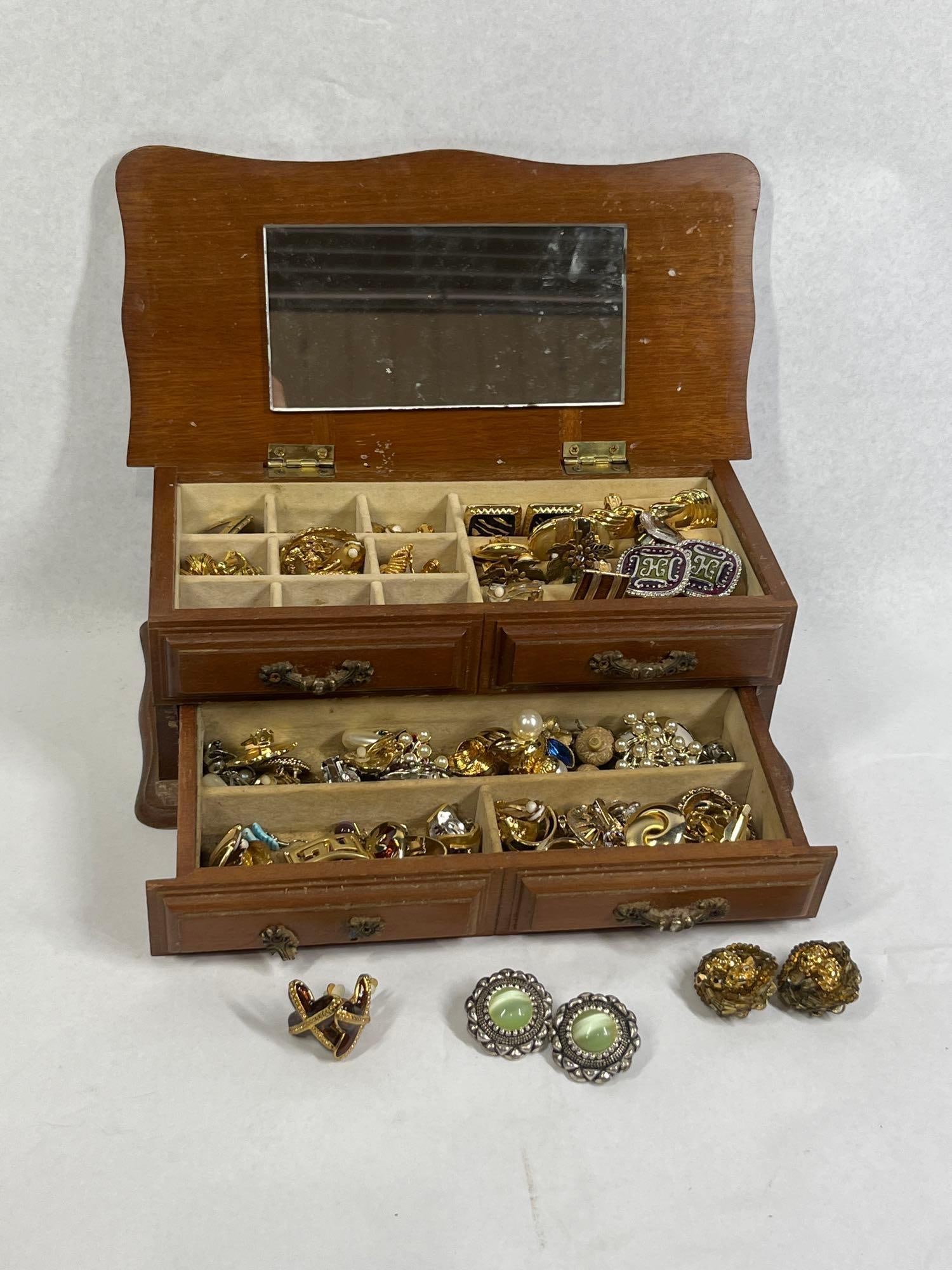 Costume Jewelry & Two-Drawer Chest: A large collection of approximately 50+ pairs and individual pieces of vintage costume jewelry, primarily consisting of clip-on and screw-back earring styles. The assortment includes pieces