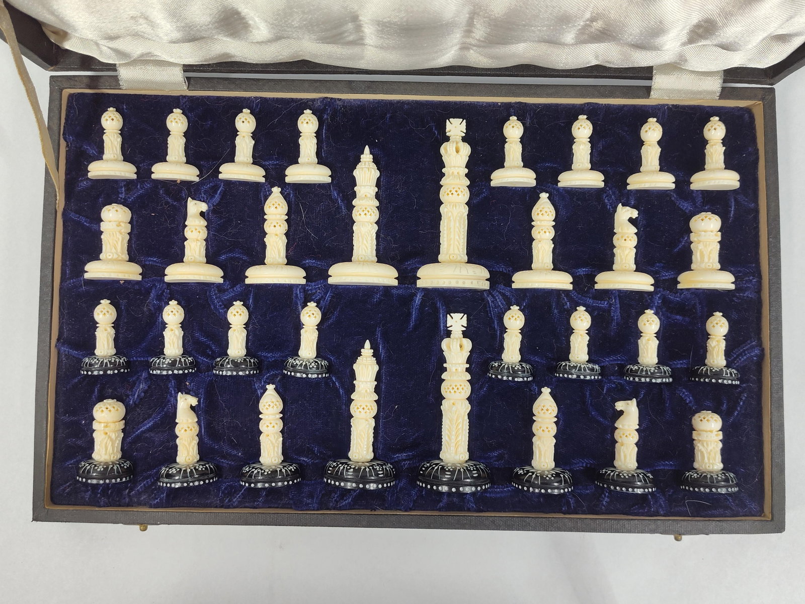 Anglo-Indian Lotus Pattern Chess Set: This set of 32 hand-carved pieces is designed in the Anglo-Indian Lotus pattern and dates from the mid-to-late 20th century. The collection consists of two opposing sides. One side is finished in a