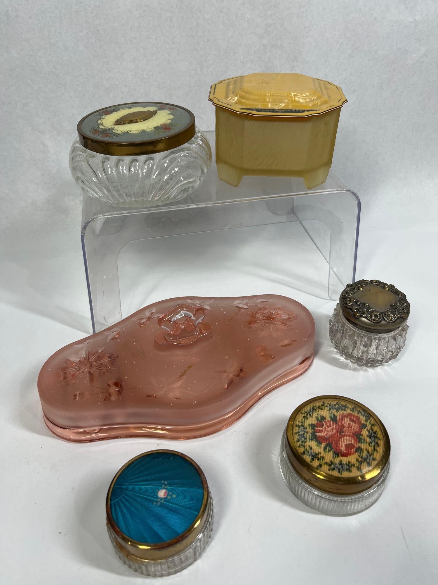 Glass Vanity Jars & Dresser Boxes: This assortment of vintage vanity and dresser items consists of various pressed and molded glass vessels from the early to mid-20th century. The group features a large kidney-shaped pink depression gl
