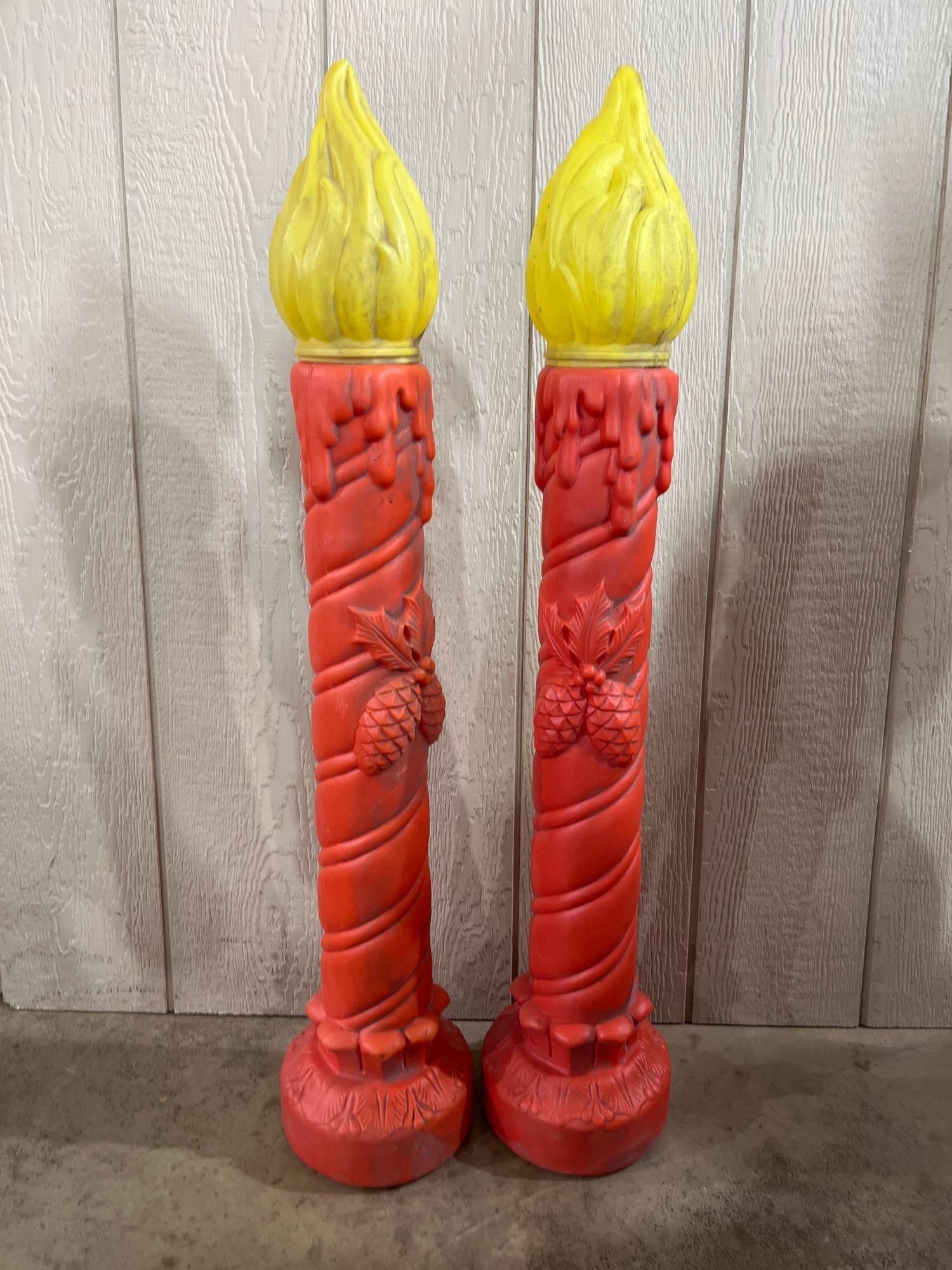 Pair Poloron Christmas Blow Molds: 38in A pair of vintage holiday blow mold decorations in the form of large candles. These items are constructed from molded plastic and feature red spiral-textured bodies and yellow flame-shaped tops.