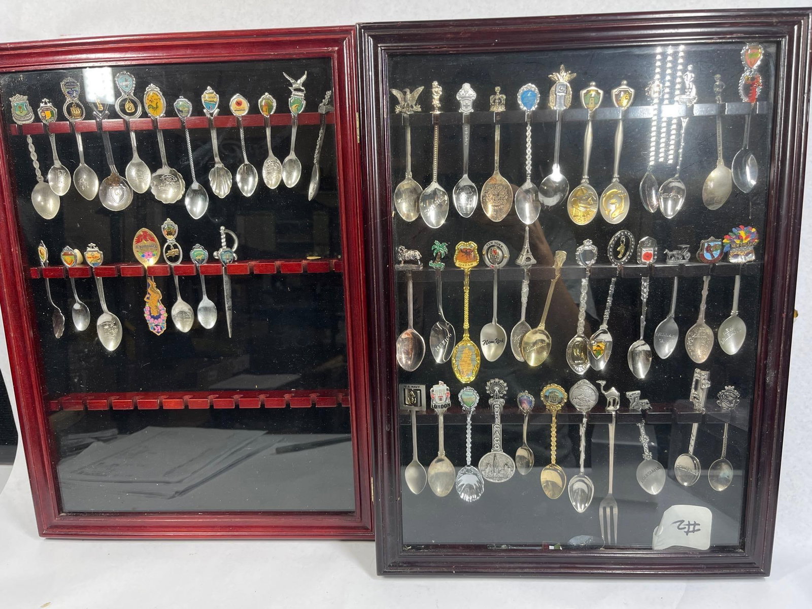 Souvenir Spoons & Opener, 2 Wood Cases: 19x14 This collection consists of multiple souvenir spoons and one sword-shaped letter opener, presented in two wall-mounted wooden display cases with glass doors and black felt-lined interiors. The s