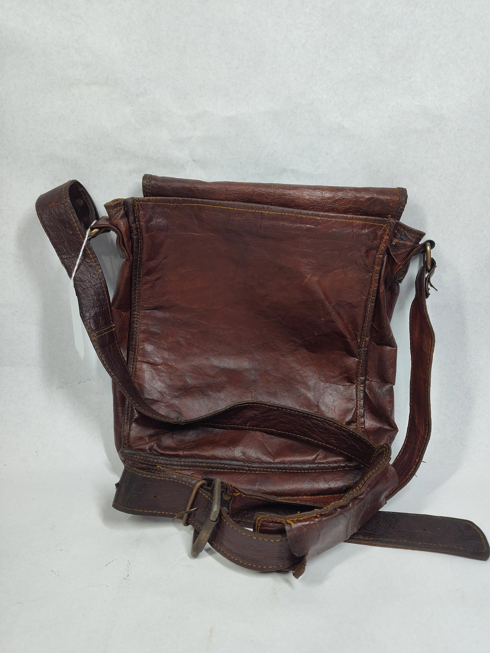 Phasha Distressed Leather Messenger Bag: This vertical messenger style bag is constructed from heavy-grain, crinkled leather in a dark brown color. The design features a large front flap that secures with two snap button closures. The bag