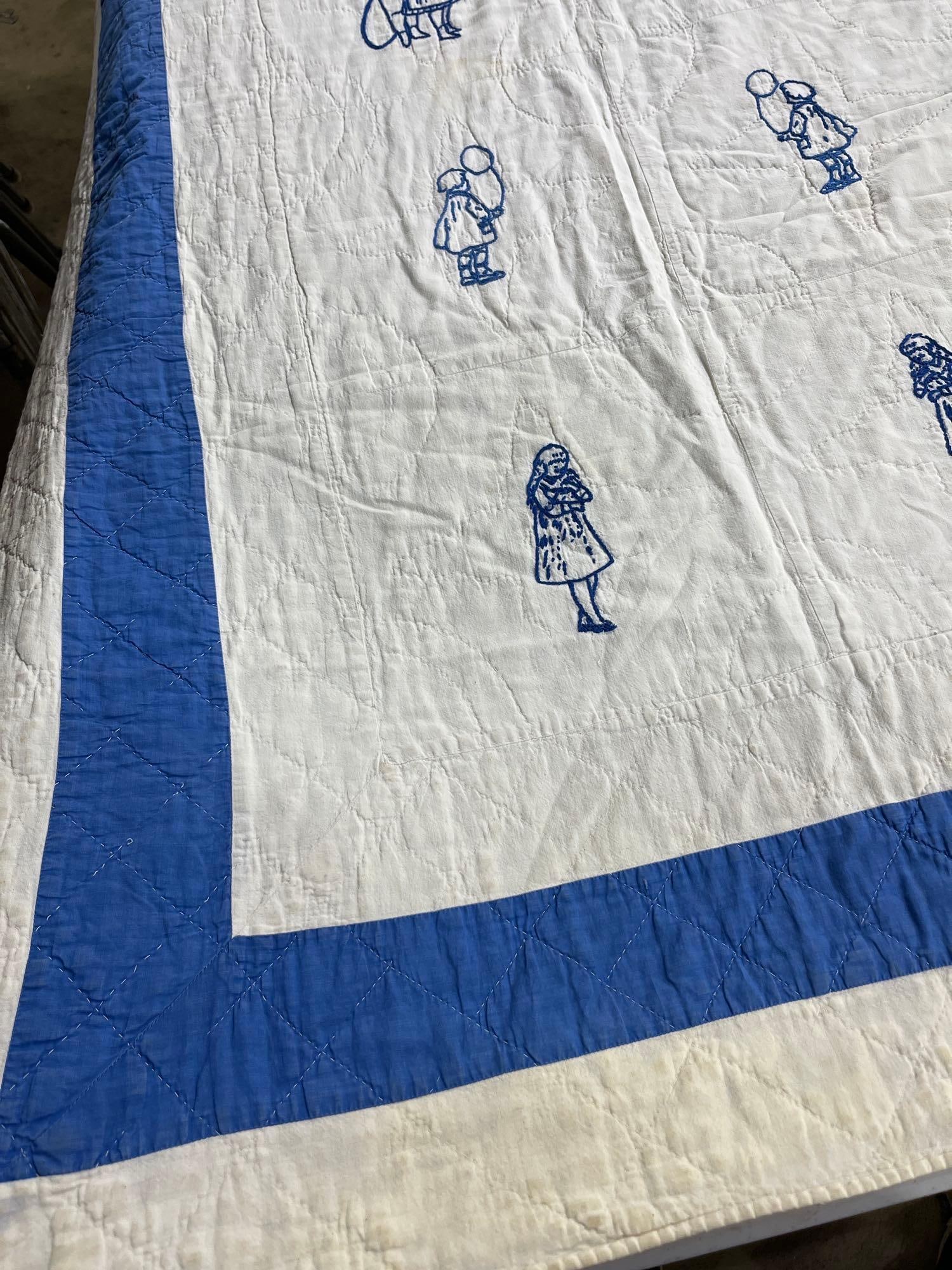 American Bluework Cotton Quilt: 82x71 This vintage American quilt is constructed from white cotton panels featuring hand-embroidered motifs in blue thread, a technique commonly referred to as bluework. The central field is composed