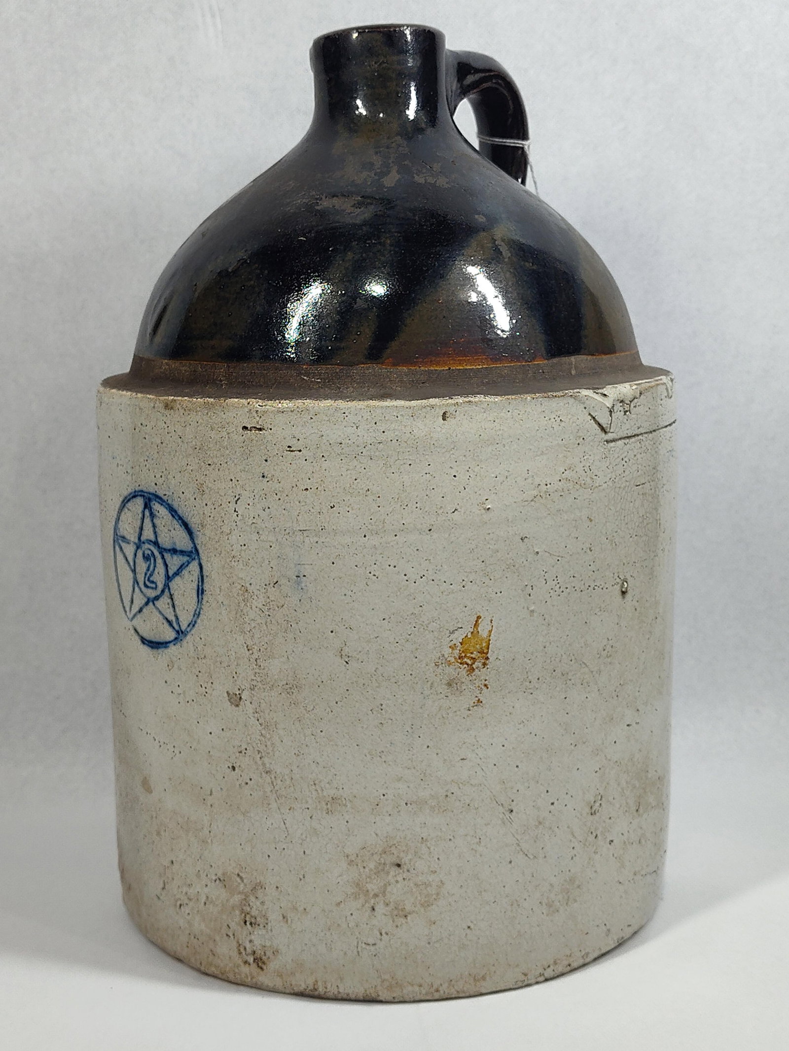 Stenciled Star Two-Tone Stoneware Jug: 13in tall, 8.5 dia.This two-gallon capacity stoneware jug features a cylindrical body with a rounded shoulder and a narrow neck topped by a single attached loop handle. The vessel is finished in a