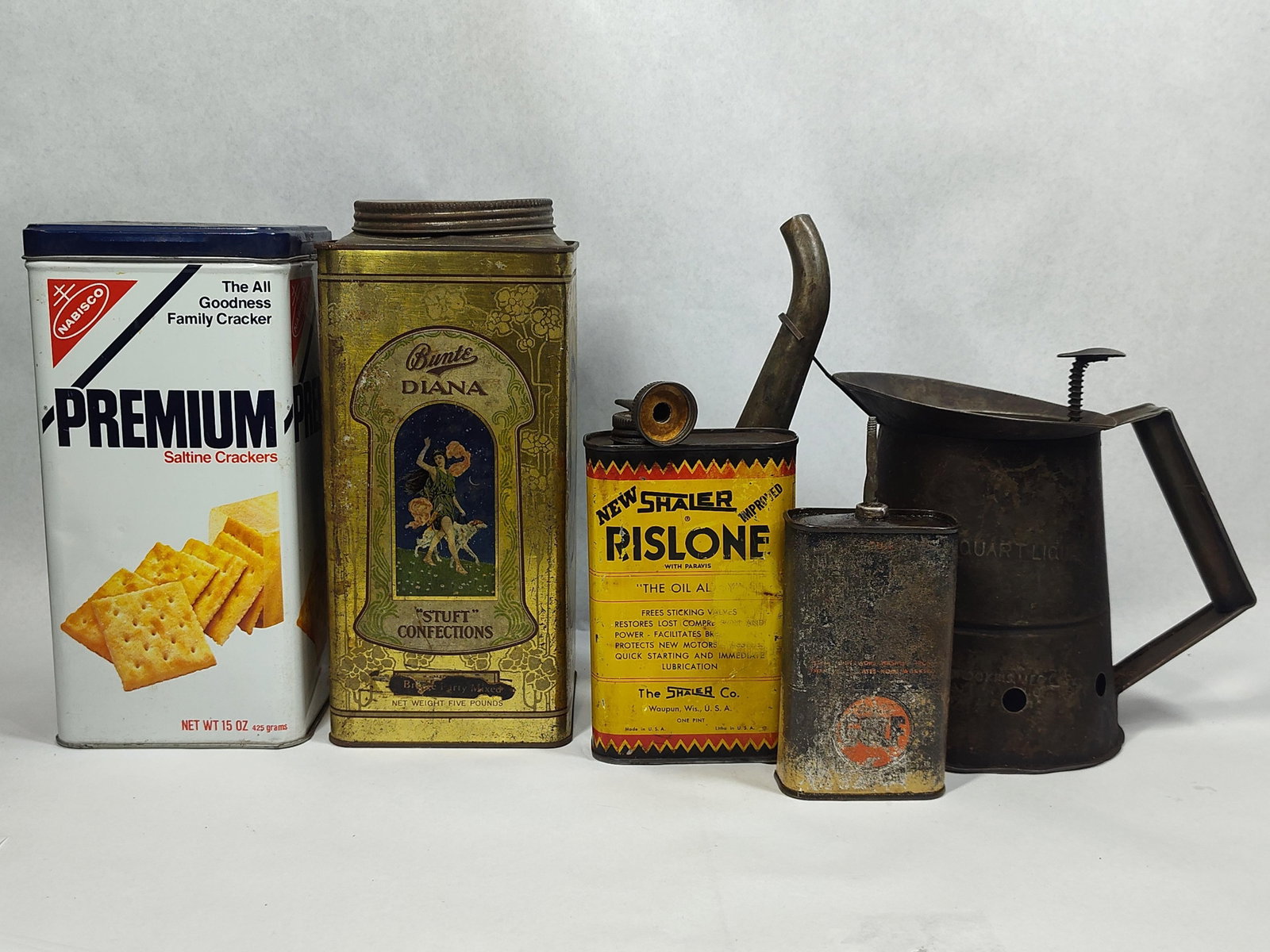Set Advertising Tins & Oil Measures: This group consists of five distinct metal containers representing food storage, confectionery, and automotive history. The collection includes a Nabisco Premium Saltine Crackers tin featuring a blue 