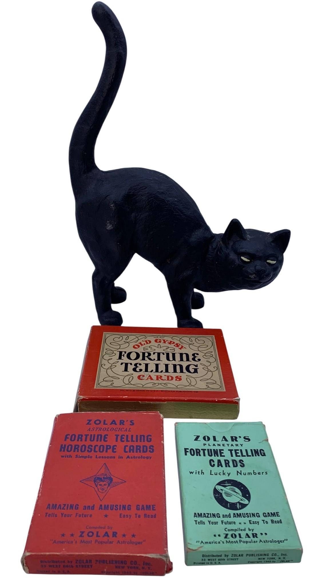 3 packs of 1940, 1942 and 1943 Gypsy Fortune Telling Cards & Vintage Cast Iron Black Cat Door Stop: Trio of 1940s fortune telling cards with the original boxes, richly hued with some age and wear to the materials and a 11" x 8" x 3 3/4" hefty cast iron black cat door stop.