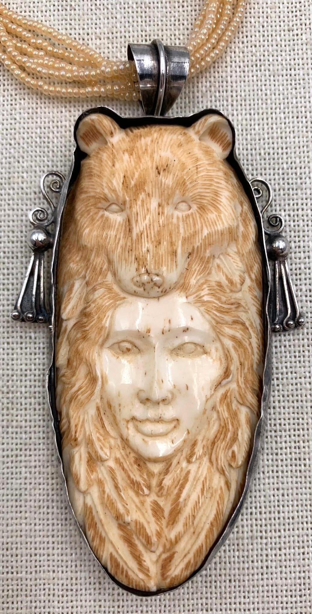 Incredible Silver Framed Hand Carved Bone Bear and Woman Totem Pendant on Italian Seed Bead Necklace: 3 1/2" pendant length, Sterling framework, intricately carved bone, SRM Italian charm at the working closure, 6 strands of petite champagne glass seed bead necklace, 18" circumference.