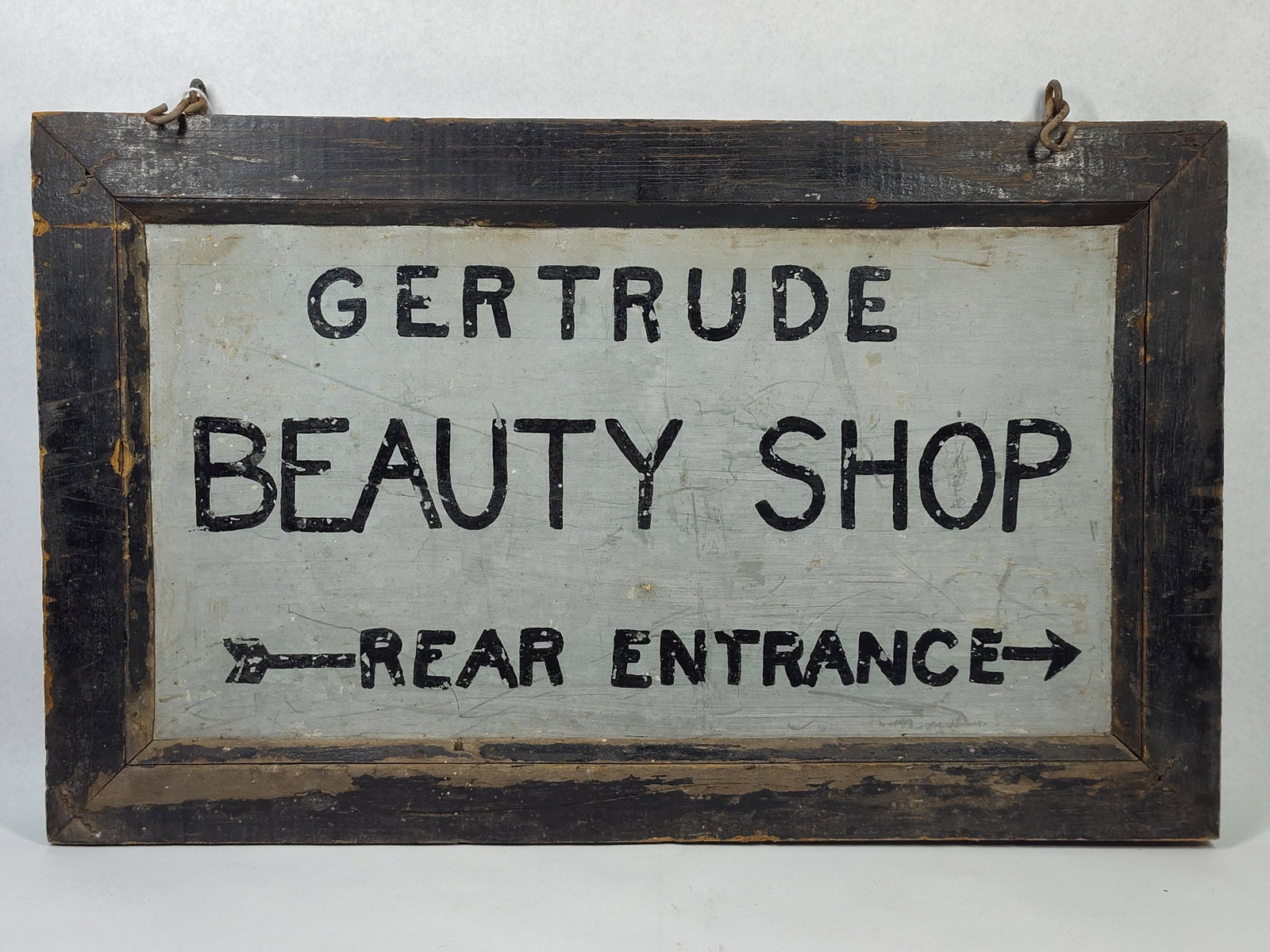 Vtg Gertrude Beauty Shop Wood Sign: 21.5x13. Tin with wood frame. A mid-20th-century hand-painted double-sided wooden directional sign for Gertrude Beauty Shop. The sign features a central painted wood panel set within a dark-stained,