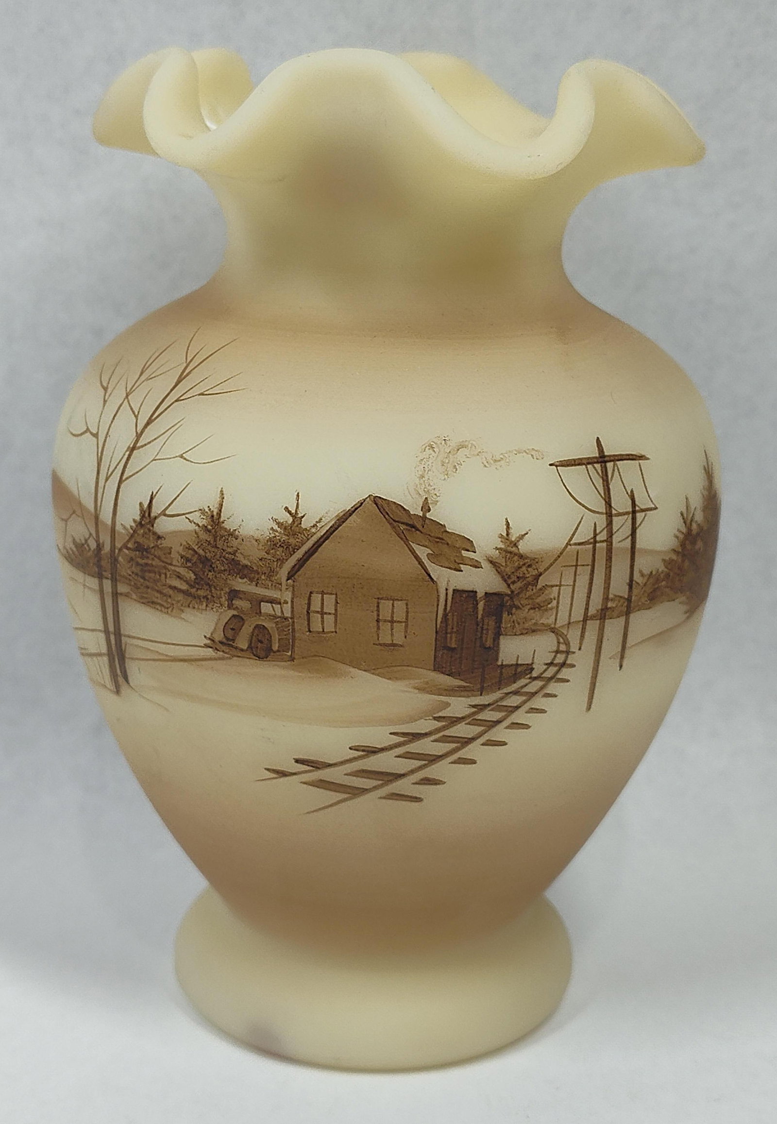 Fenton S. Bryan Station Satin Glass: 6.5 inches. This Fenton Art Glass vase is decorated in the Down By The Station pattern and was hand-painted by artist Susan Bryan. The vessel features a ruffled rim, a bulbous midsection, and a
