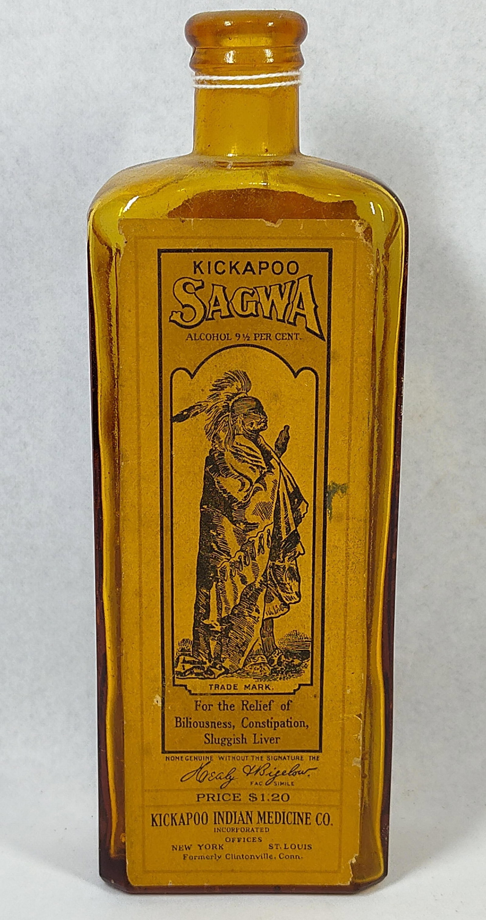 Kickapoo Sagwa Amber Bottle w/ Labels: 8.5 in. This antique amber glass bottle was produced by the Kickapoo Indian Medicine Company for their signature remedy, Kickapoo Sagwa. The rectangular bottle features vertical embossing on one side