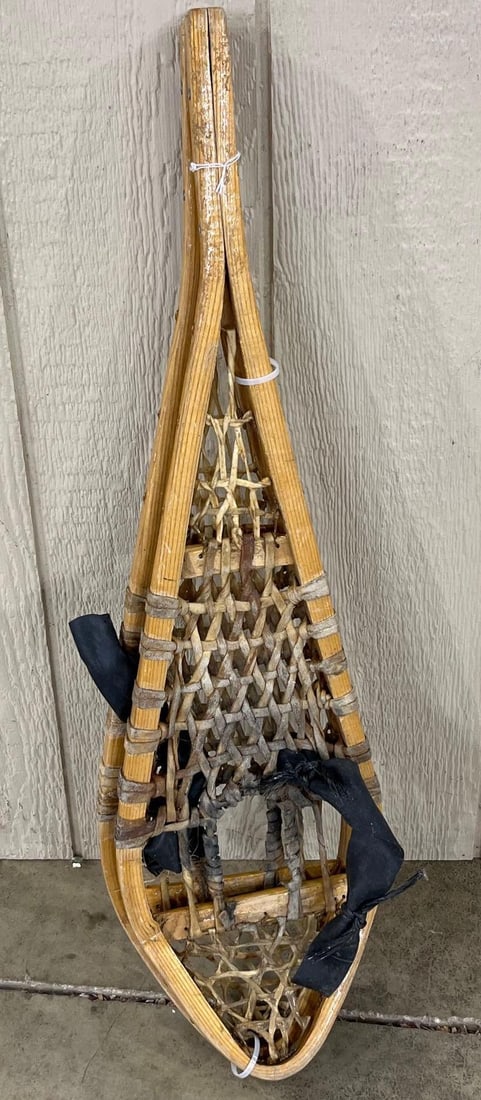 Pair Vtg Huron Style Rawhide Snowshoes: 33 inches. A pair of vintage traditional wooden snowshoes designed in the Huron or Michigan style. The frames are constructed from steam-bent wood, likely ash, and terminate in a long, pointed tail.