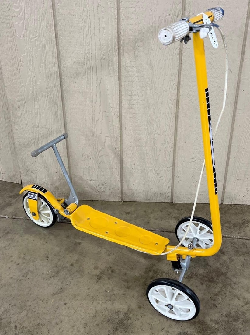 Vtg Honda Kick 'N Go 3-Wheeled Scooter: A vintage Honda Kick 'N Go three-wheeled scooter manufactured in Japan. The scooter features a yellow-painted tubular metal frame and a stamped metal footboard. It is constructed with two wheels