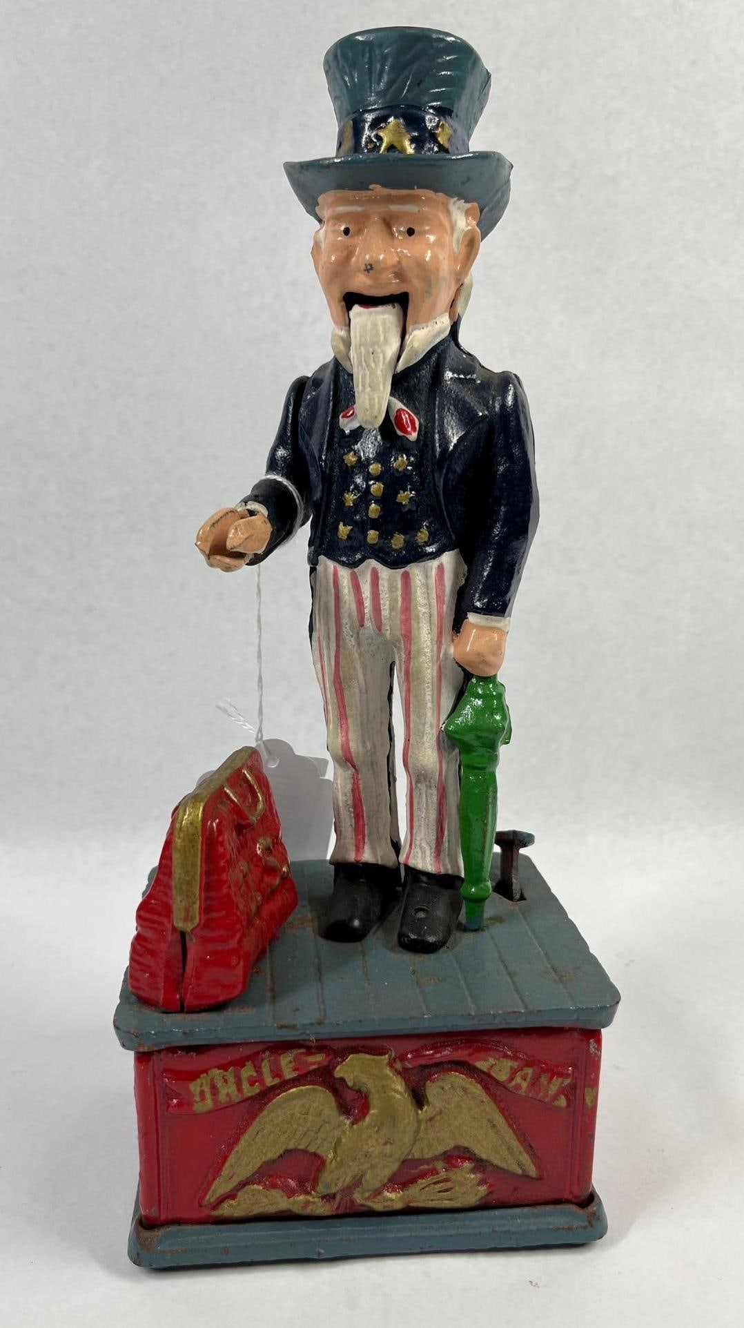 Himark Uncle Sam Mechanical Bank: 11 in tall. This is a cast iron mechanical bank produced by Himark, featuring a polychrome painted figure of Uncle Sam. This item is a mid to late 20th-century reproduction of the original late 19th-c