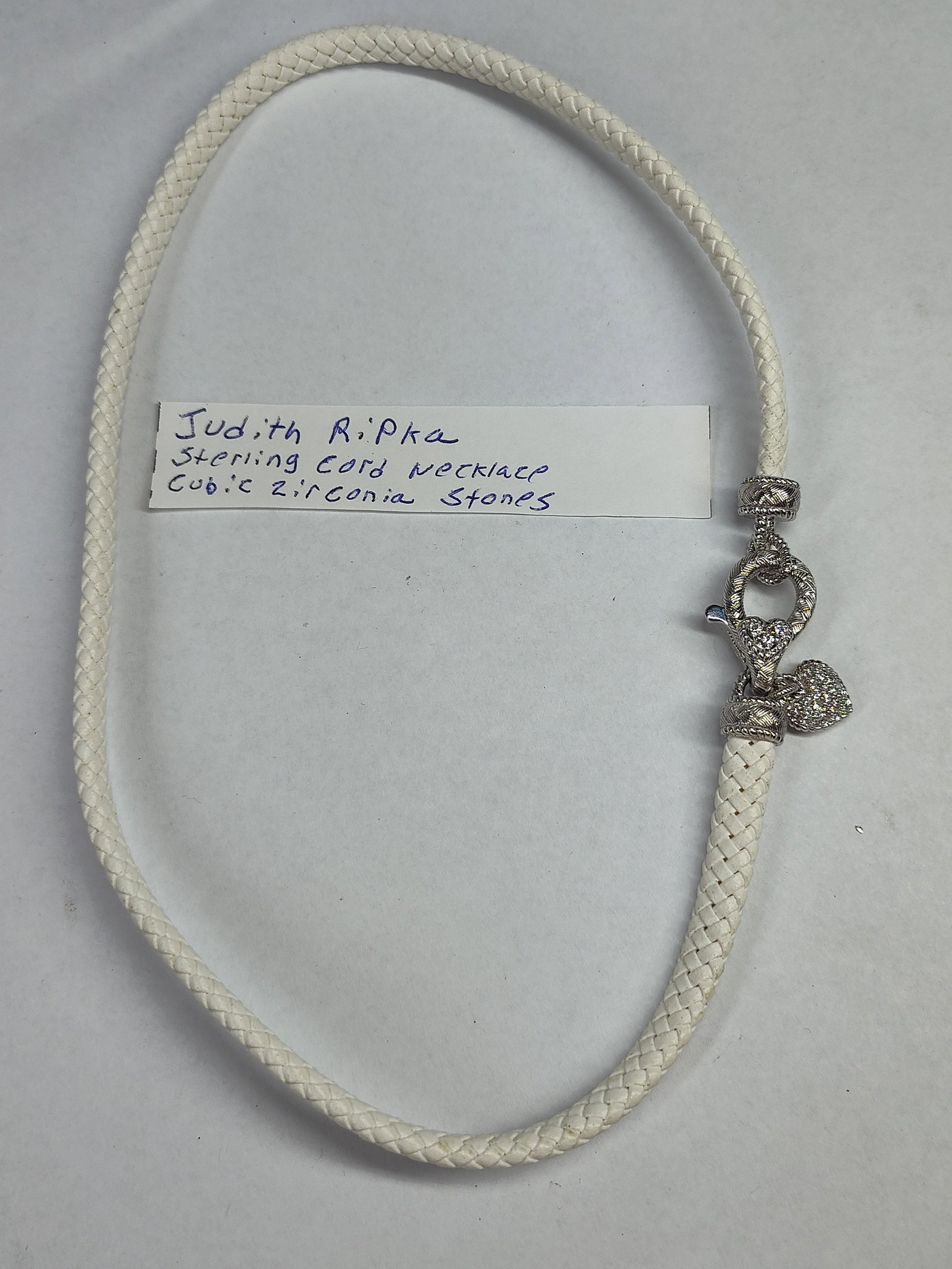 Judith Ripka Attr. Str. Heart Necklace: A designer cord necklace attributed to Judith Ripka featuring a white braided cord and sterling silver decorative elements. The piece showcases the designer's signature Berge rope-textured aesthet