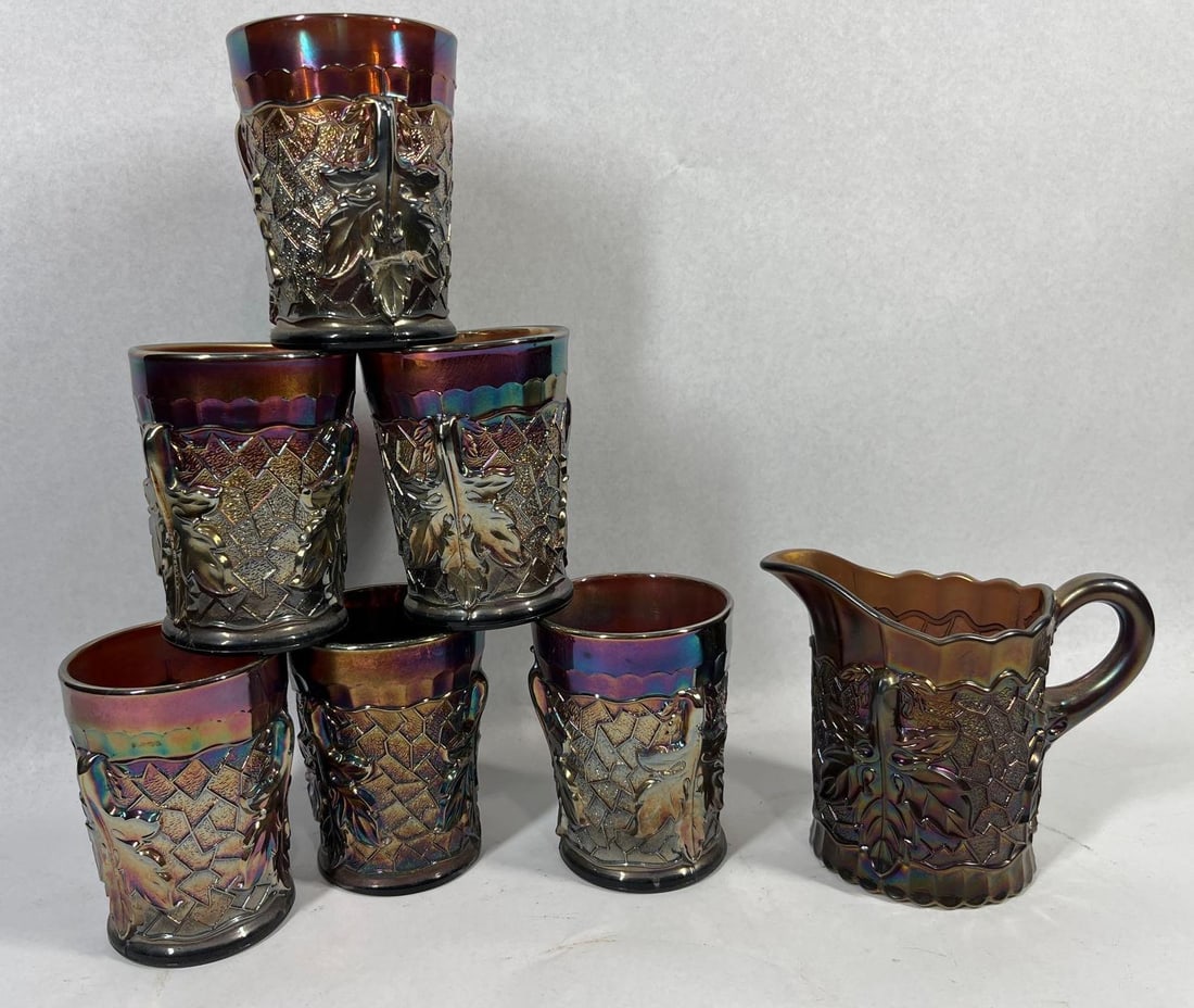 Maple Leaf Amethyst Carnival Glass Set: A 7-piece amethyst carnival glass beverage set in the Maple Leaf pattern, attributed to Northwood. This collection consists of one pitcher and six matching tumblers. Each piece is crafted from