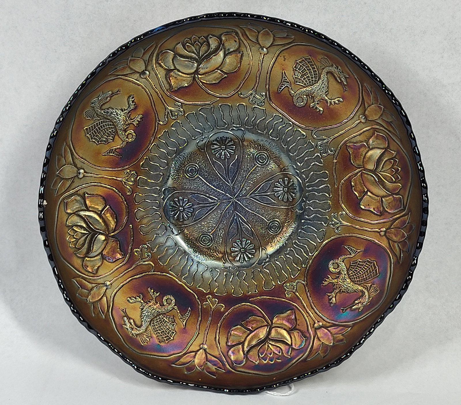 Cobalt Dragon & Lotus Carnival Bowl: This iridescent carnival glass bowl is attributed to the Fenton Art Glass Company and features the Dragon and Lotus pattern. It is composed of pressed cobalt blue base glass with a factory-applied