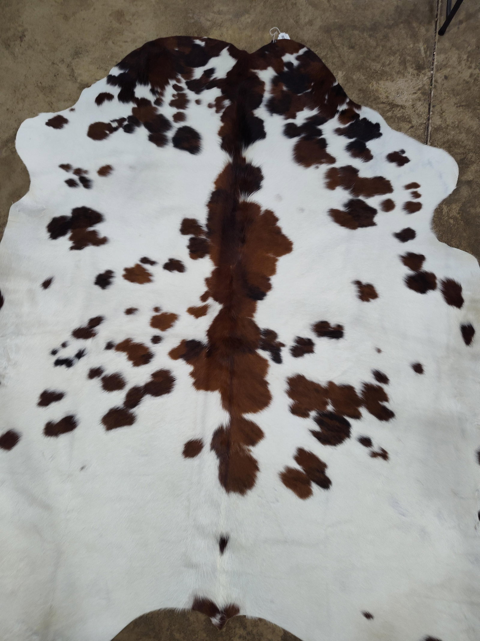 Colombian Tricolor Natural Cowhide Rug: Approximately 5 ft 6 inches x 7 feet. This is a natural hair-on-hide rug of Colombian origin, characterized by its tricolor pattern and organic silhouette. The design features a white ground with