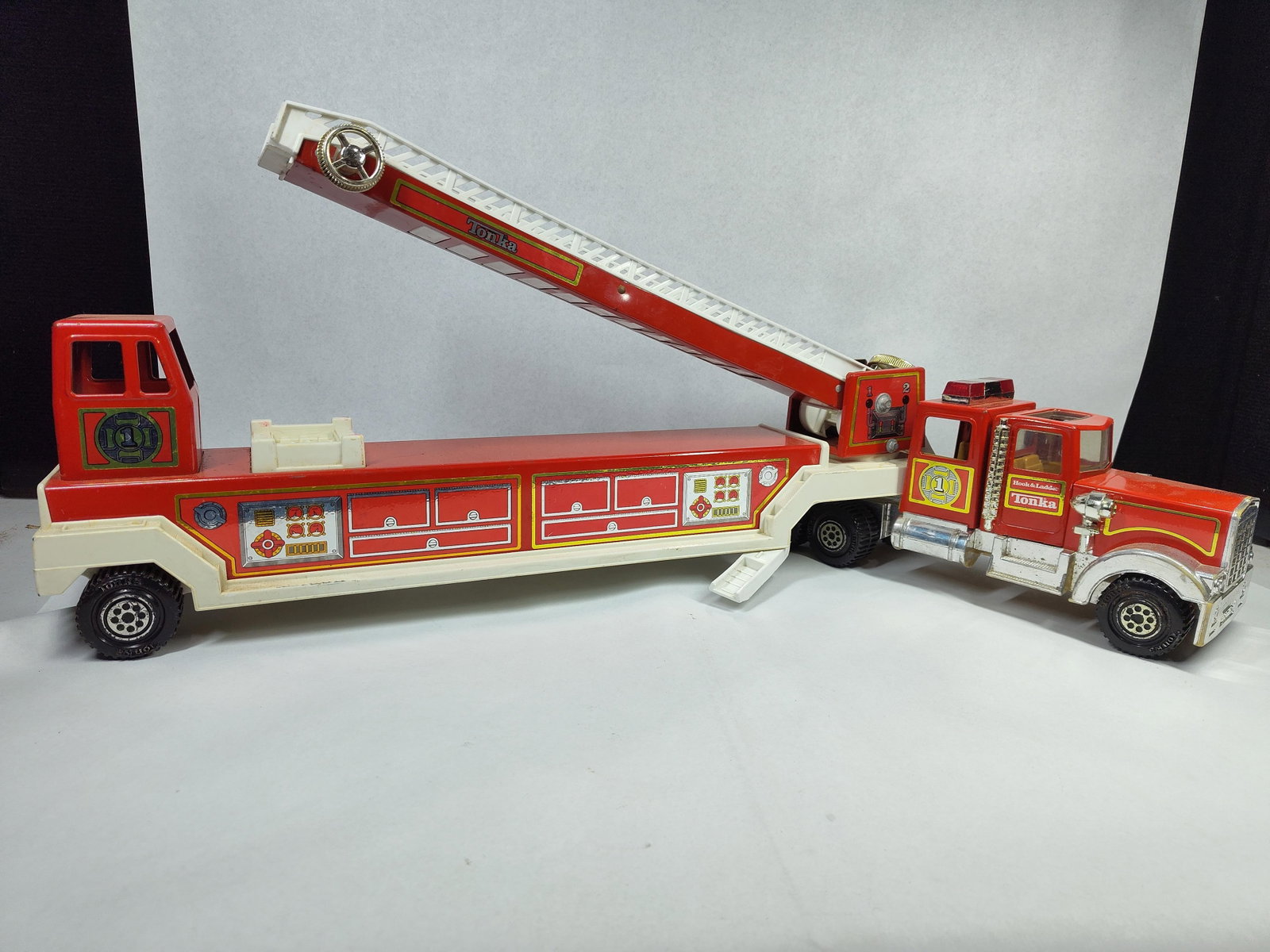 Vtg Tonka No. 1 Hook & Ladder Truck: 33 in. This vintage articulated fire truck is manufactured by Tonka and represents the Hook and Ladder Number 1 model. The vehicle is primarily constructed from pressed steel with a red and white