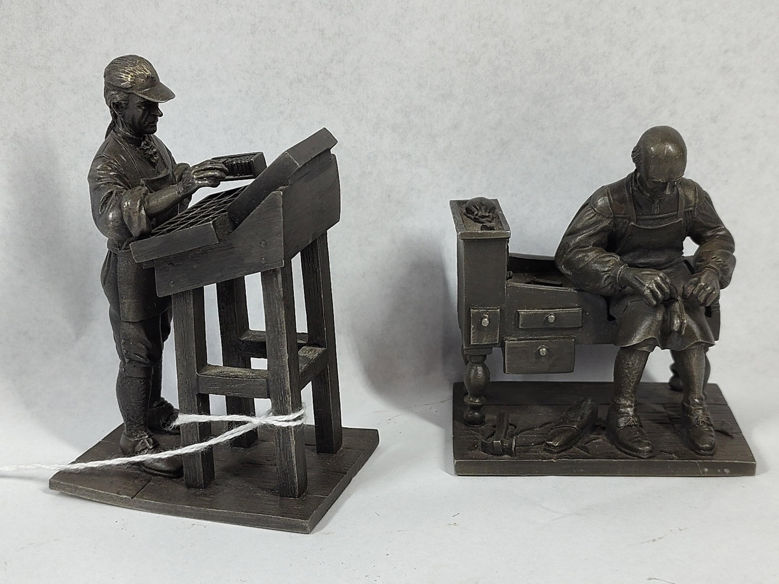 Franklin Mint Pewter Printer/Shoemaker: 3.5 to 4 in tall. The Franklin Mint People of Colonial America series cast fine pewter figurines featuring a consistent dark grey patina. This pair includes one titled The Printer and one titled The