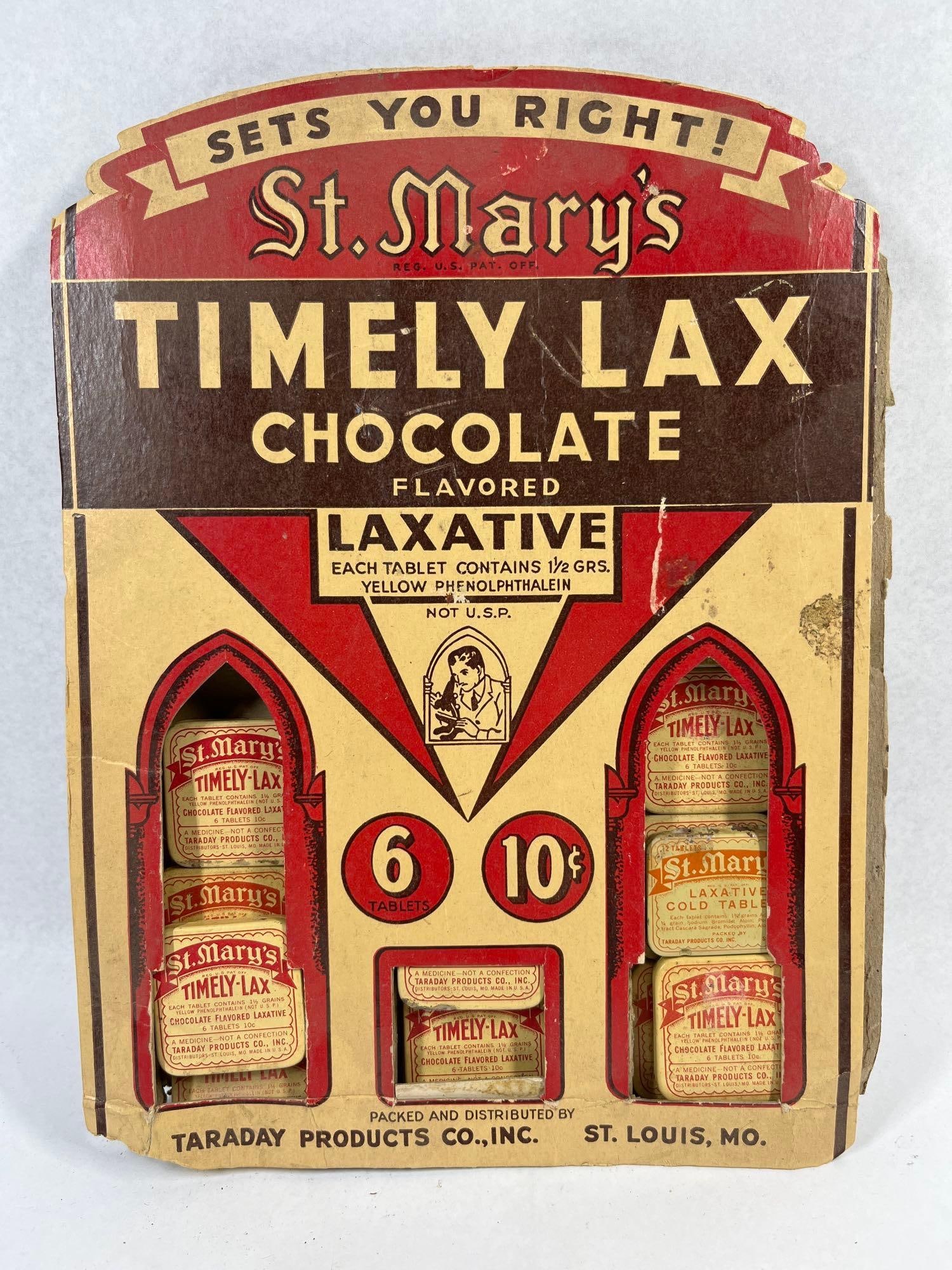 St. Mary's Timely-Lax Display & Tins: This lot features a mid-20th-century point-of-sale advertising display for St. Mary's brand medicinal products. The die-cut cardboard counter-top display is designed with a tripartite
