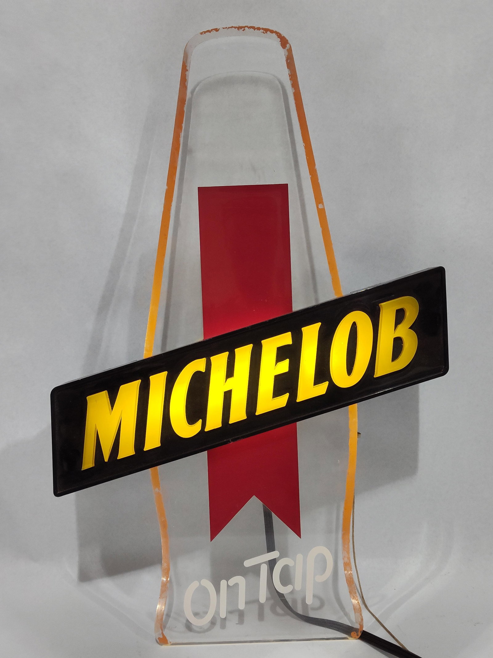 Vtg Michelob On Tap Lighted Beer Sign: 20x13. This vintage illuminated brewery sign features the Michelob brand, produced by Anheuser-Busch. The sign is constructed with a clear acrylic panel cut into a stylized beer bottle silhouette,
