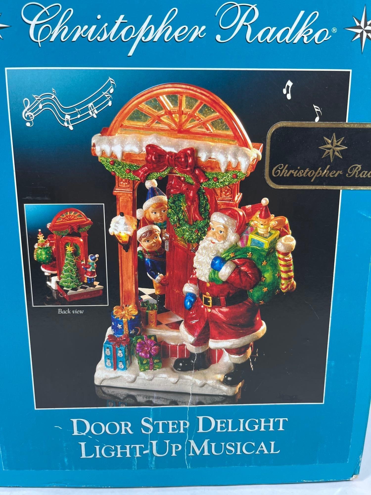 Christopher Radko Door Step Figurine: This Christopher Radko Door Step Delight holiday figurine depicts a festive Christmas scene. The three-dimensional piece shows Santa Claus standing on a snow-dusted doorstep carrying a green sack