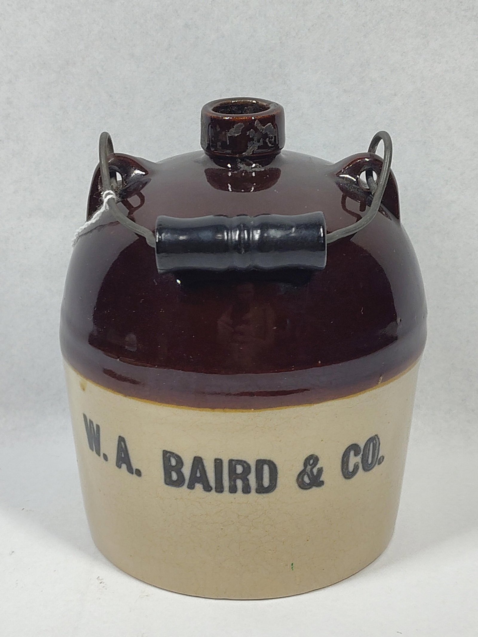 or <Advertising" have higher: 6 inches.This is a beehive or shoulder-style stoneware advertising jug, identified by the stenciled mark on the body for the wholesale distributor W.A. Baird and Co. The jug features a traditional