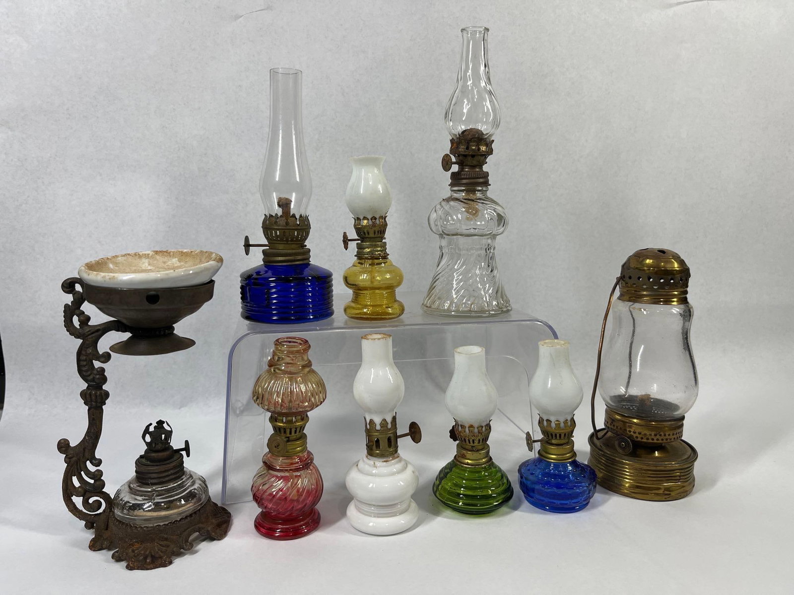 9 Mini Lamps & Vapo-Cresolene Vaporizer: This collection consists of nine non-electric liquid-fuel lighting and medical items. The lot includes an antique medical vaporizer produced by the Vapo-Cresolene Company, featuring an ornate cast iro