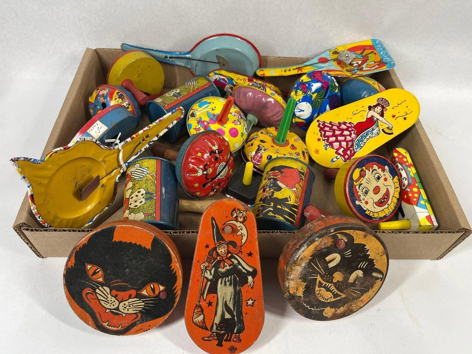 U.S. Metal Toy & American Noise Makers: An assortment of lithographed tin noise makers and party favors from the mid-20th century. The collection includes a variety of forms such as handle-mounted clappers, cylindrical shakers, bell-shaped