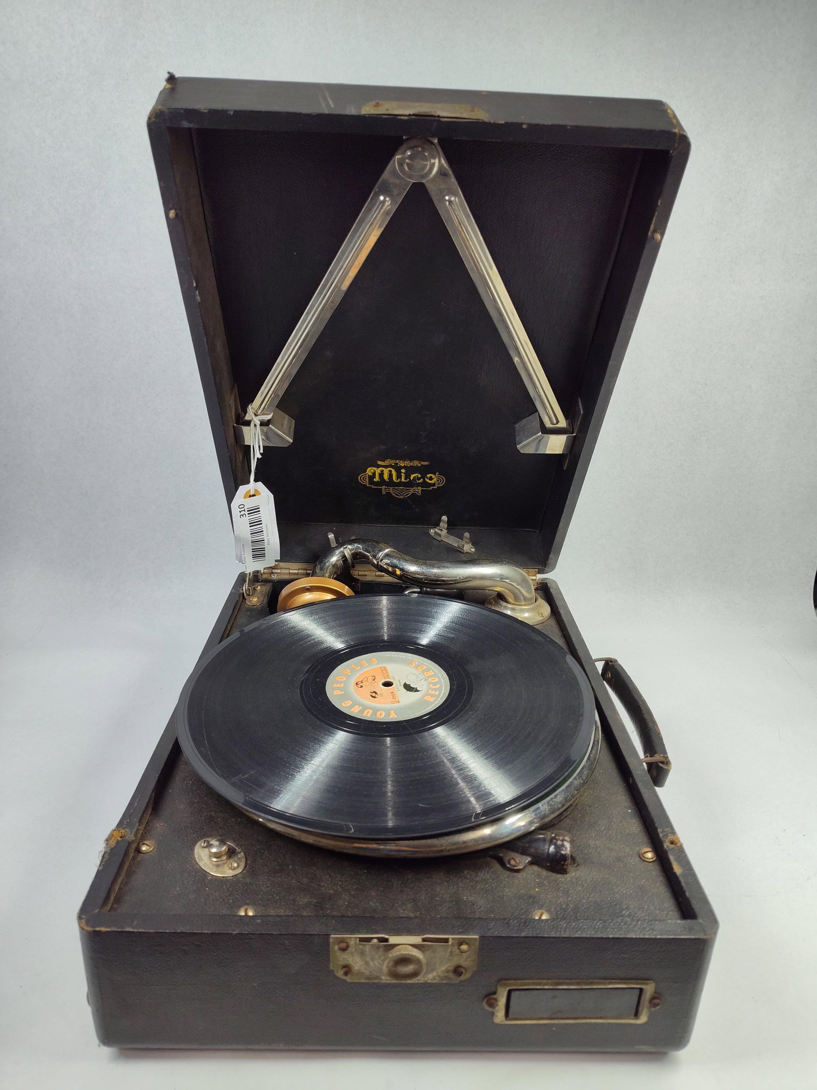 Mico Portable Suitcase Gramophone: A portable acoustic phonograph manufactured by Mico, likely dating to the early 20th century. The device is contained within a wooden suitcase-style case covered in a black textured rexine-type materi