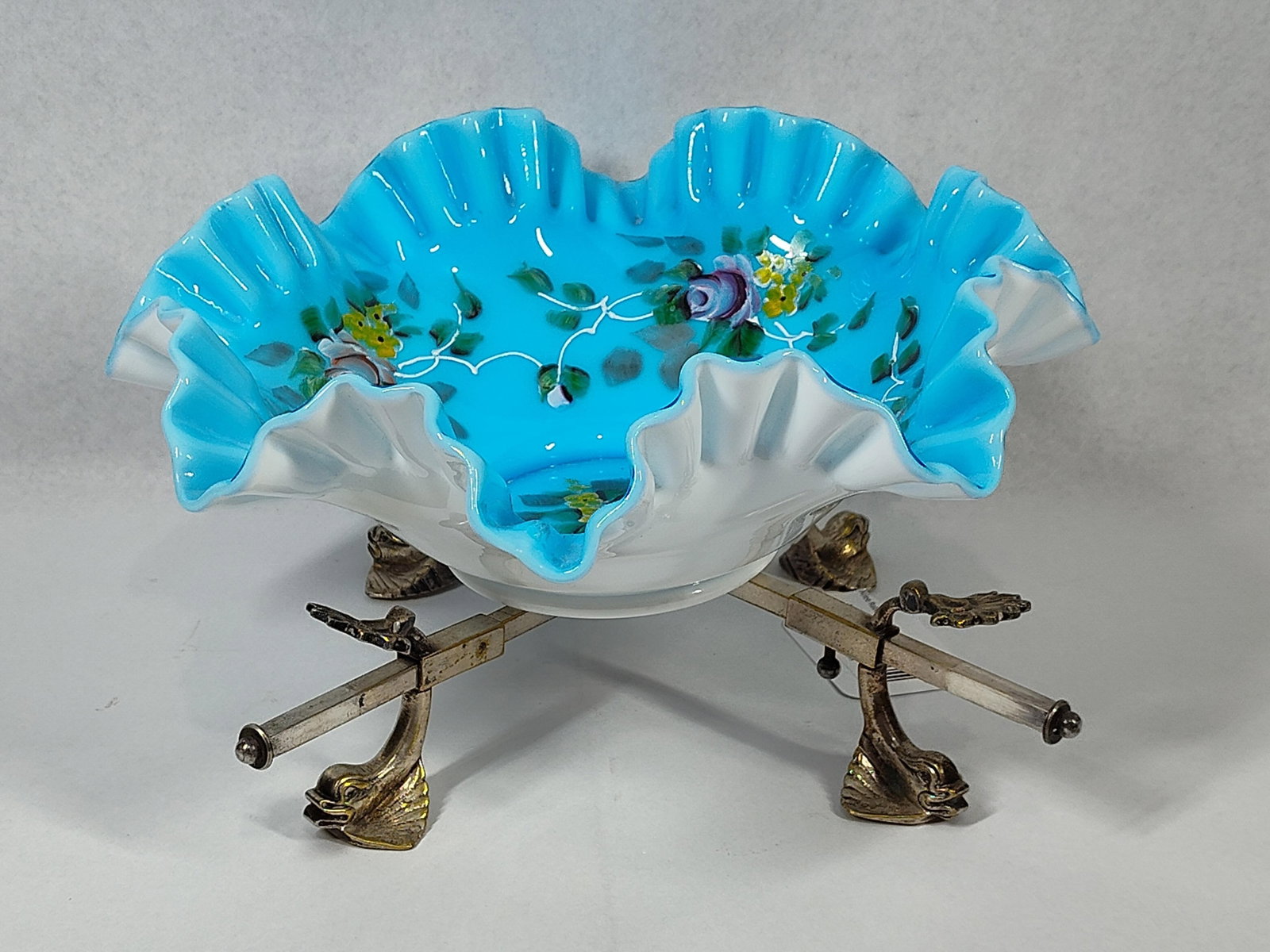 Bonwit Teller Cased Glass Bowl & Stand: 11x6 This two-piece set features a hand-painted cased art glass bowl resting on an adjustable decorative metal stand. The bowl is constructed with a vibrant turquoise-blue interior and a white