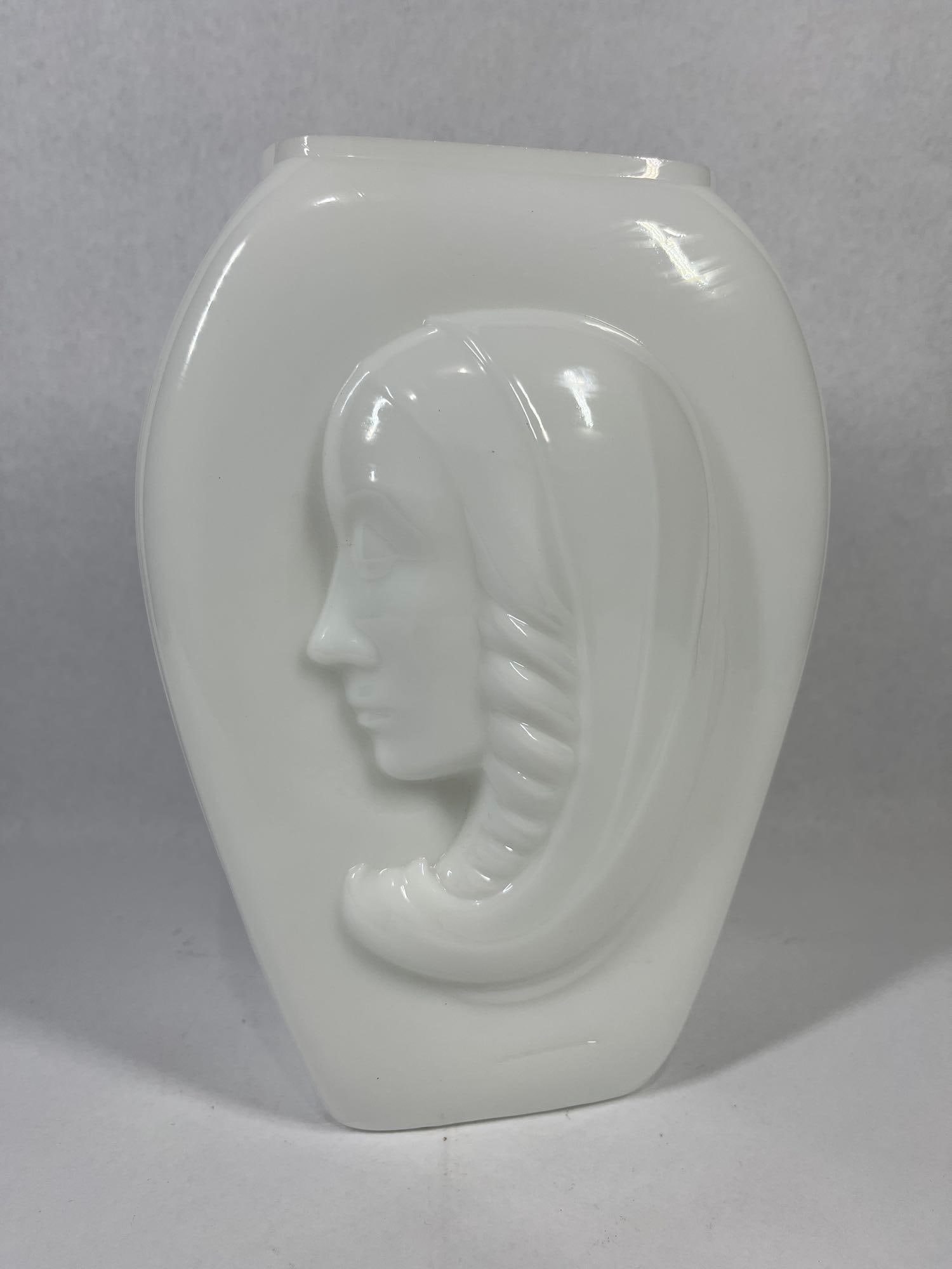 Art Deco Madonna Profile Glass Vase: 10.5x7x3 Small chip on rim. Attributed to the Phoenix Consolidated Glass Company, this Art Deco style vase is crafted from opaque white milk glass. The vessel features a flattened ovoid form with a pr