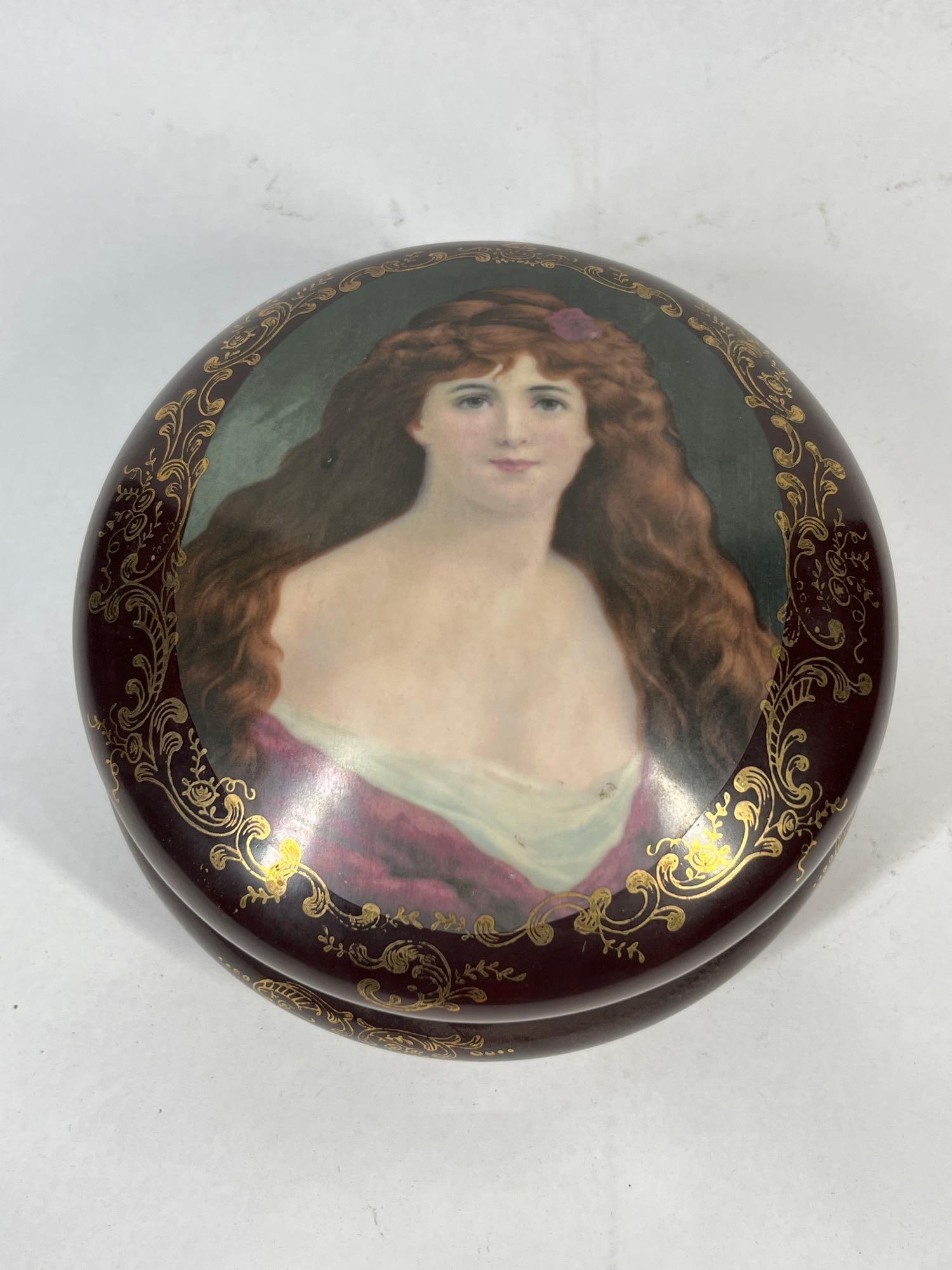 Victorian Portrait Porc. Trinket Box: 7.5x4 This two-piece circular porcelain box features a domed lid decorated with a central portrait of a young woman with long auburn hair and a pink floral accent. The portrait is a transfer-decorated