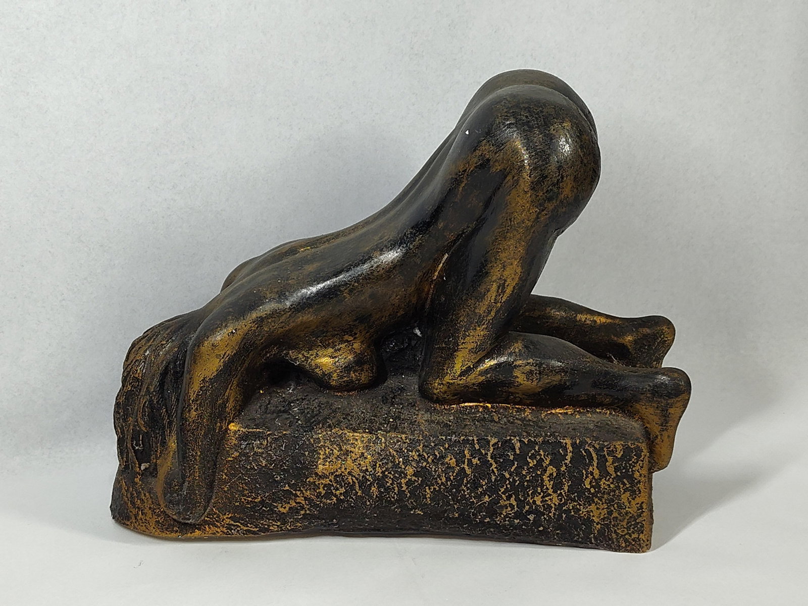 Modernist Kneeling Nude Plaster Bank: 13x6x10 This decorative novelty coin bank is modeled in the style of Auguste Rodin's Danaid, depicting a prostrate, kneeling female figure with her head resting on a textured rectangular base and 