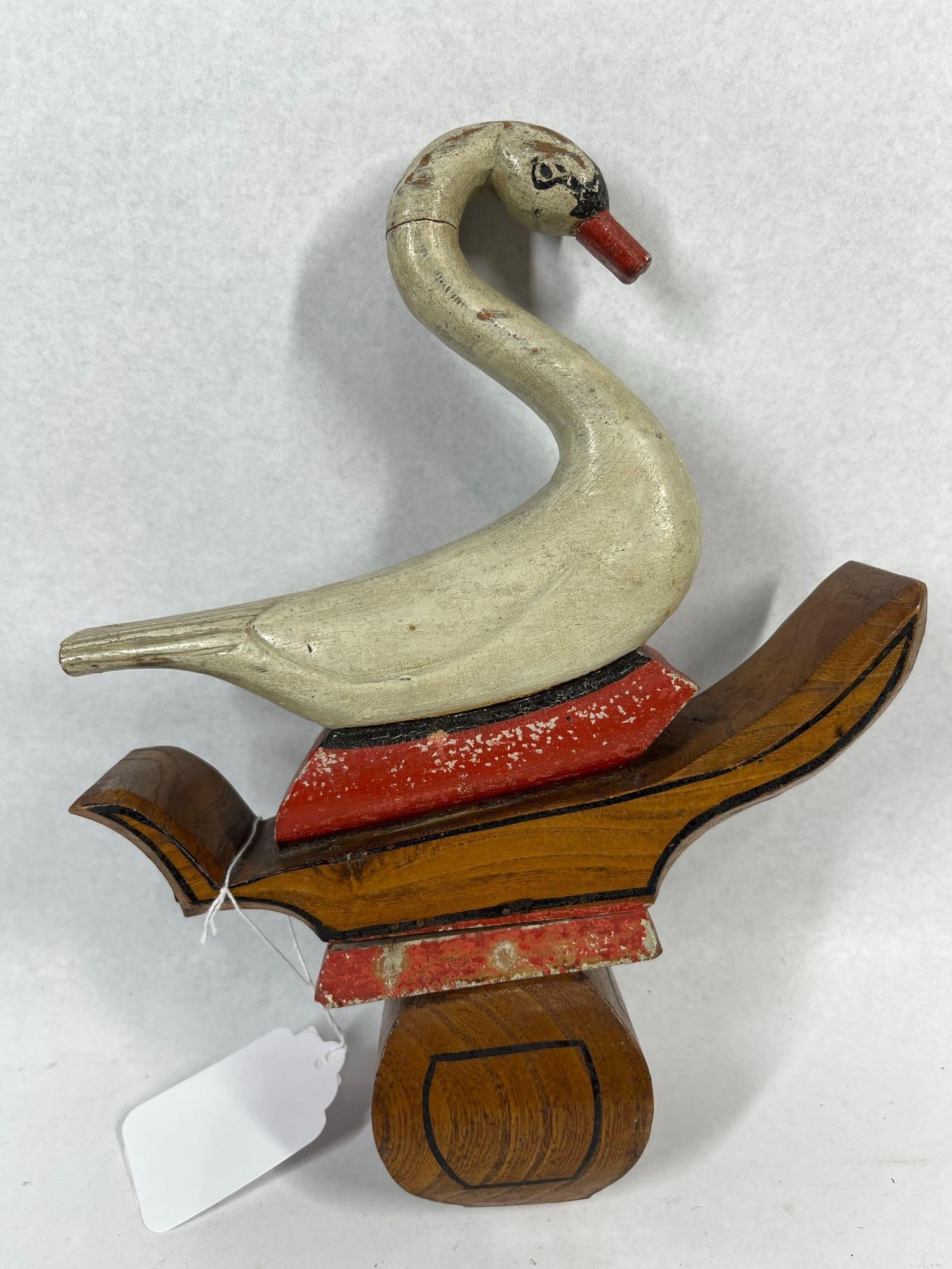 Hand-Carved Painted Wood Folk Art Swan: 9x11 This is a hand-carved and painted wooden folk art figure depicting a swan. The swan features a long, curved neck, a painted black facial mask, and a red-painted beak. The bird is mounted onto a s