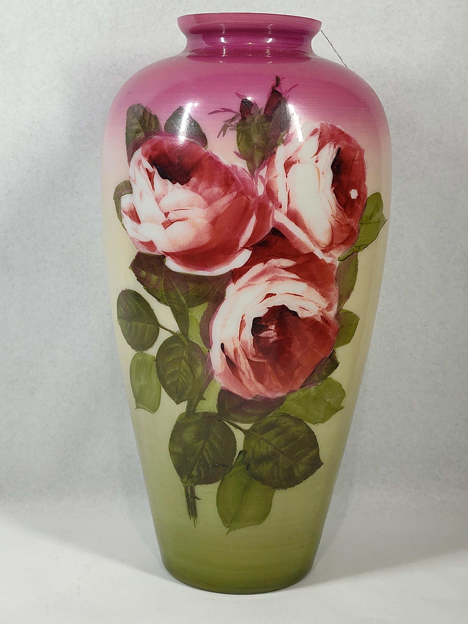 Hand Painted Rose Cased Satin Glass: 14.5 in. This cased satin glass vase features a white interior layer and a matte-finished exterior. The body is decorated with a hand-painted floral spray of three blooming roses in red, pink, and