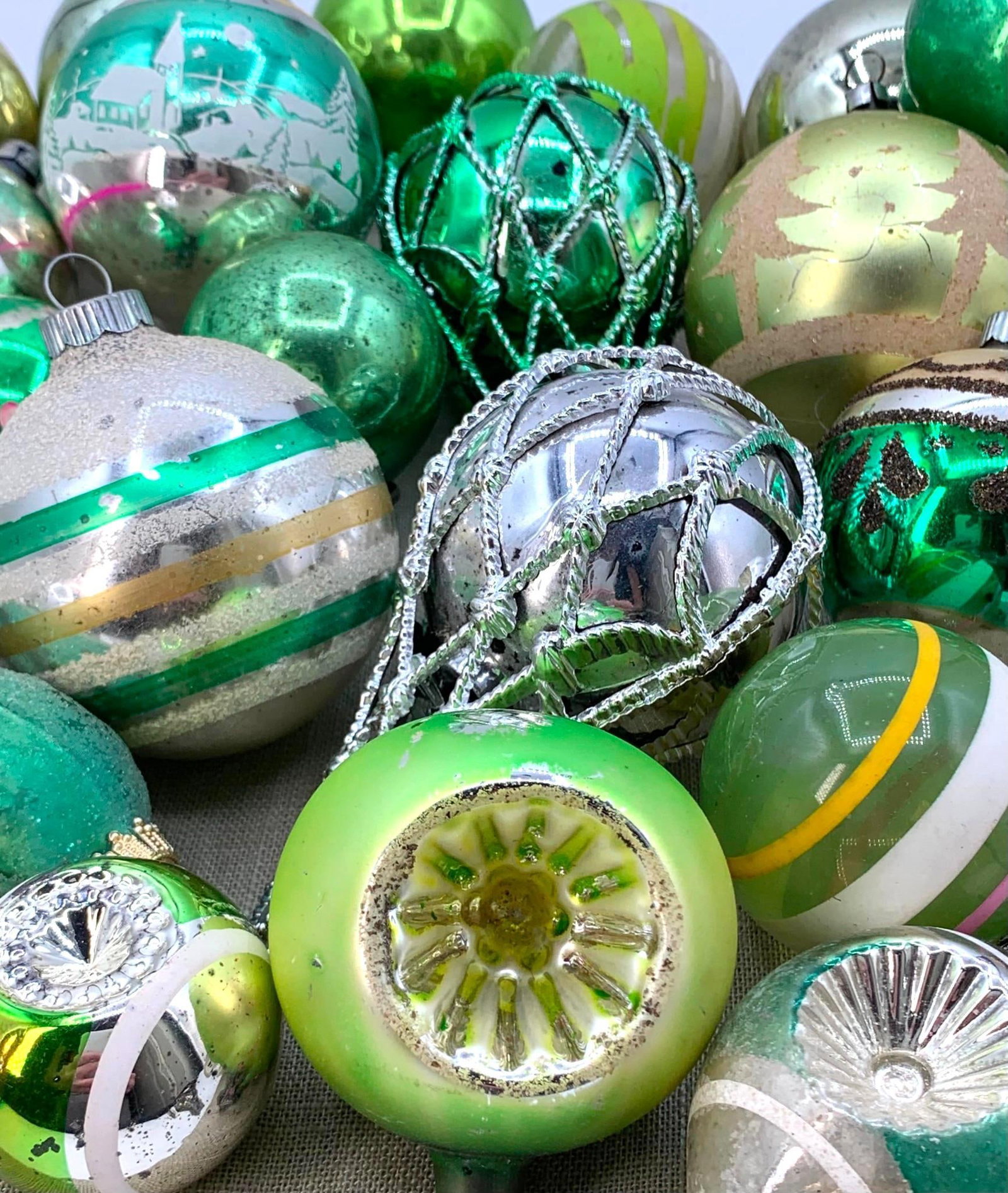 Vtg Blown Glass Christmas Ornaments: This assortment features a variety of vintage blown glass Christmas ornaments, predominantly in shades of green, silver, and gold. The collection includes various forms such as spherical baubles,