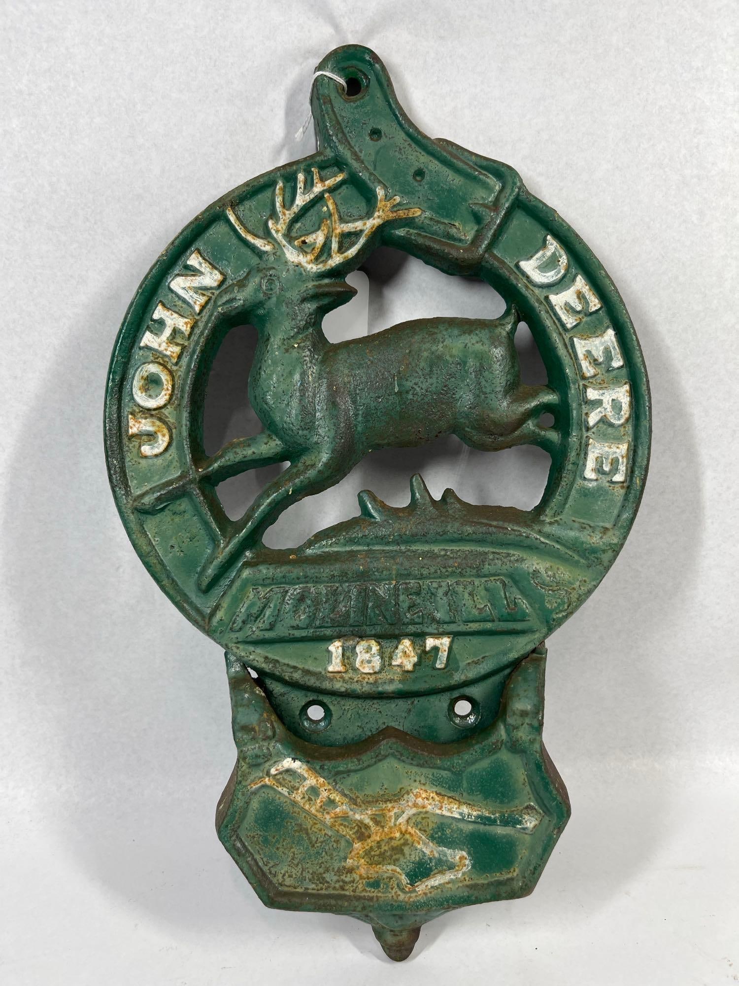 John Deere 1847 Cast Iron Letter Holder: 16x10 A cast iron wall pocket featuring promotional branding for the John Deere company. The piece is designed with a circular upper frame depicting a leaping deer in relief. Below the deer, a